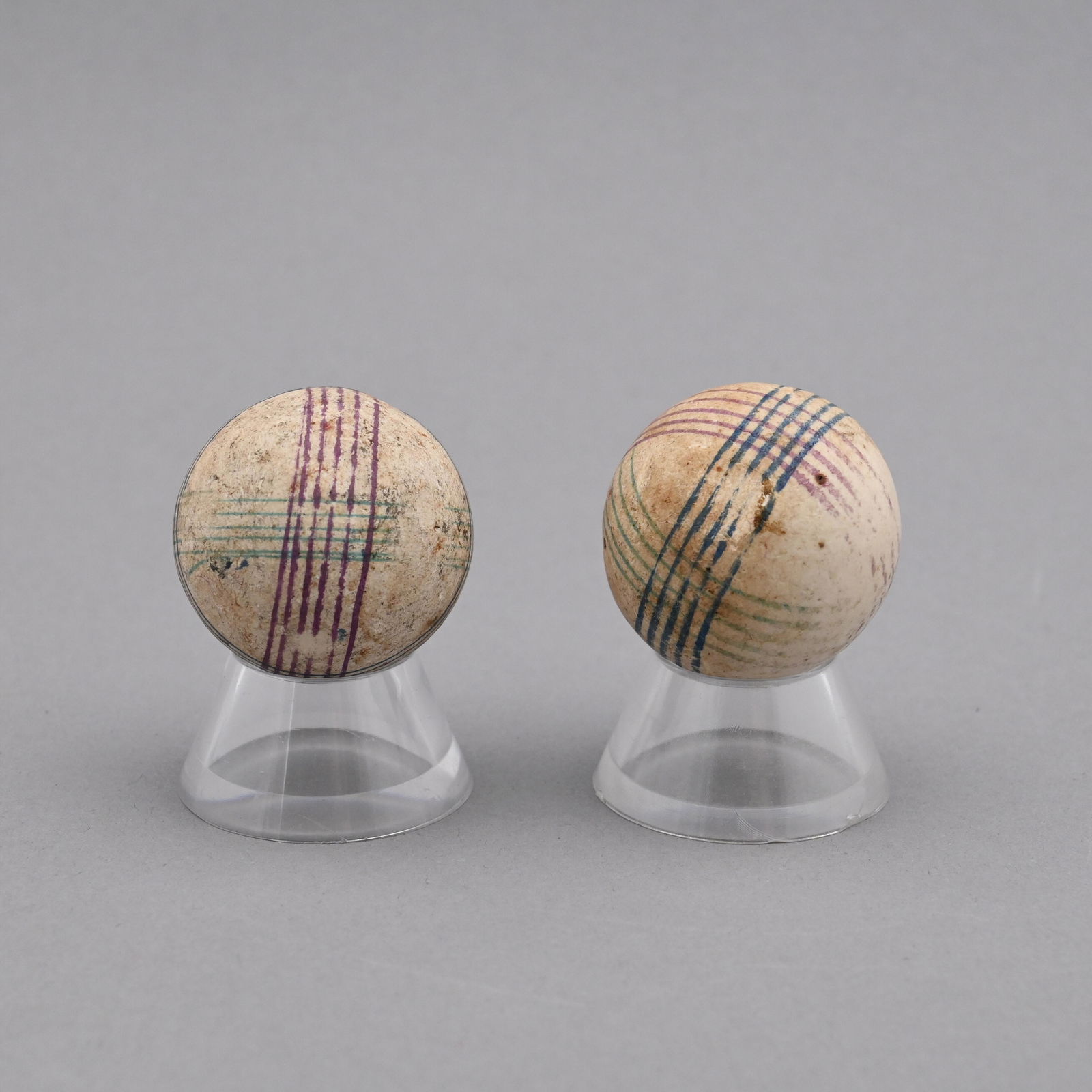Ten Large Painted China Marbles: Surrounded by horizontal and vertical red and blue banding on a white ground. Approximate range of diam: 1 31/128 to 1 35/128 in.