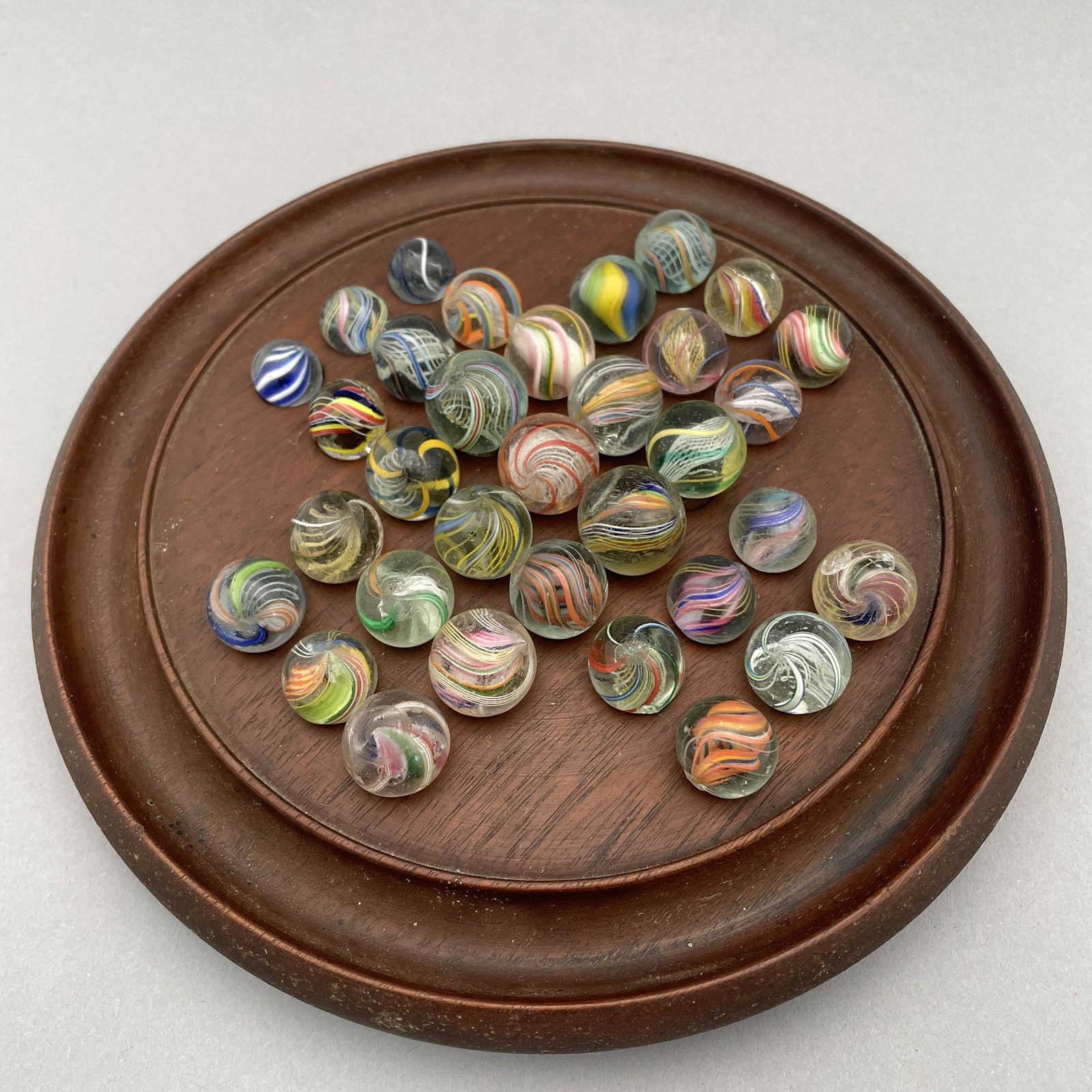 Solitaire Board with Thirty-Three Marbles: The marbles handmade and comprising swirls. Approximate range of diam: 35/64 to 103/128 in. Board: Diam: 8.25 in., D: 1.125 in.