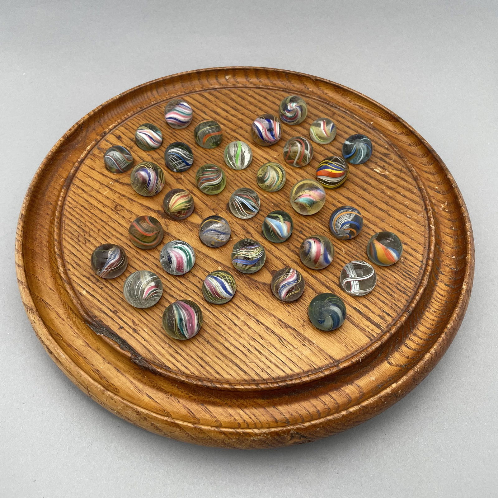Solitaire Board with Thirty-Three Marbles: The marbles handmade and comprising swirls. Approximate range of diam: 79/128 to 97/128 in. Board: Diam: 9.75 in., D: 1.125 in.