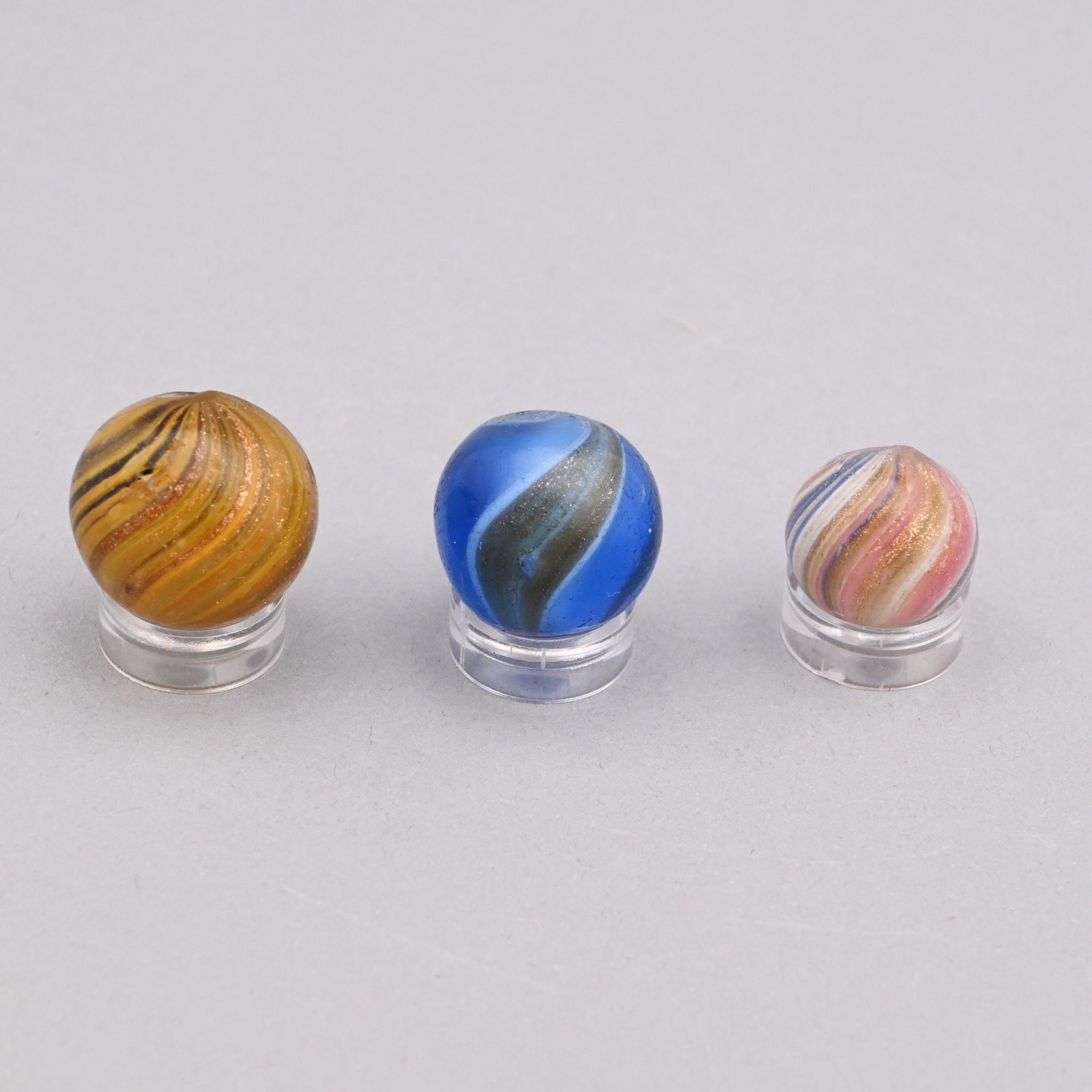 Three Banded Gold Lutz Marbles: In shades of yellow, pink and blue. Approximate range of diam: 79/128 to 101/128 in.