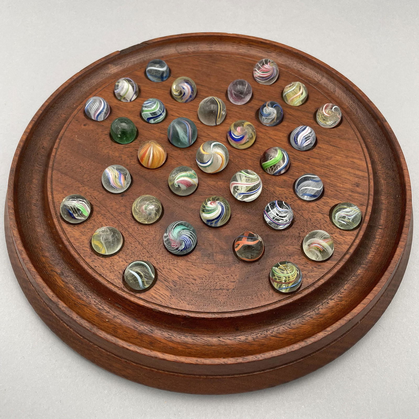 Solitaire Board with Thirty-Three Marbles: The marbles handmade and comprising swirls and onion skins. Approximate range of diam: 35/64 to 45/64 in.