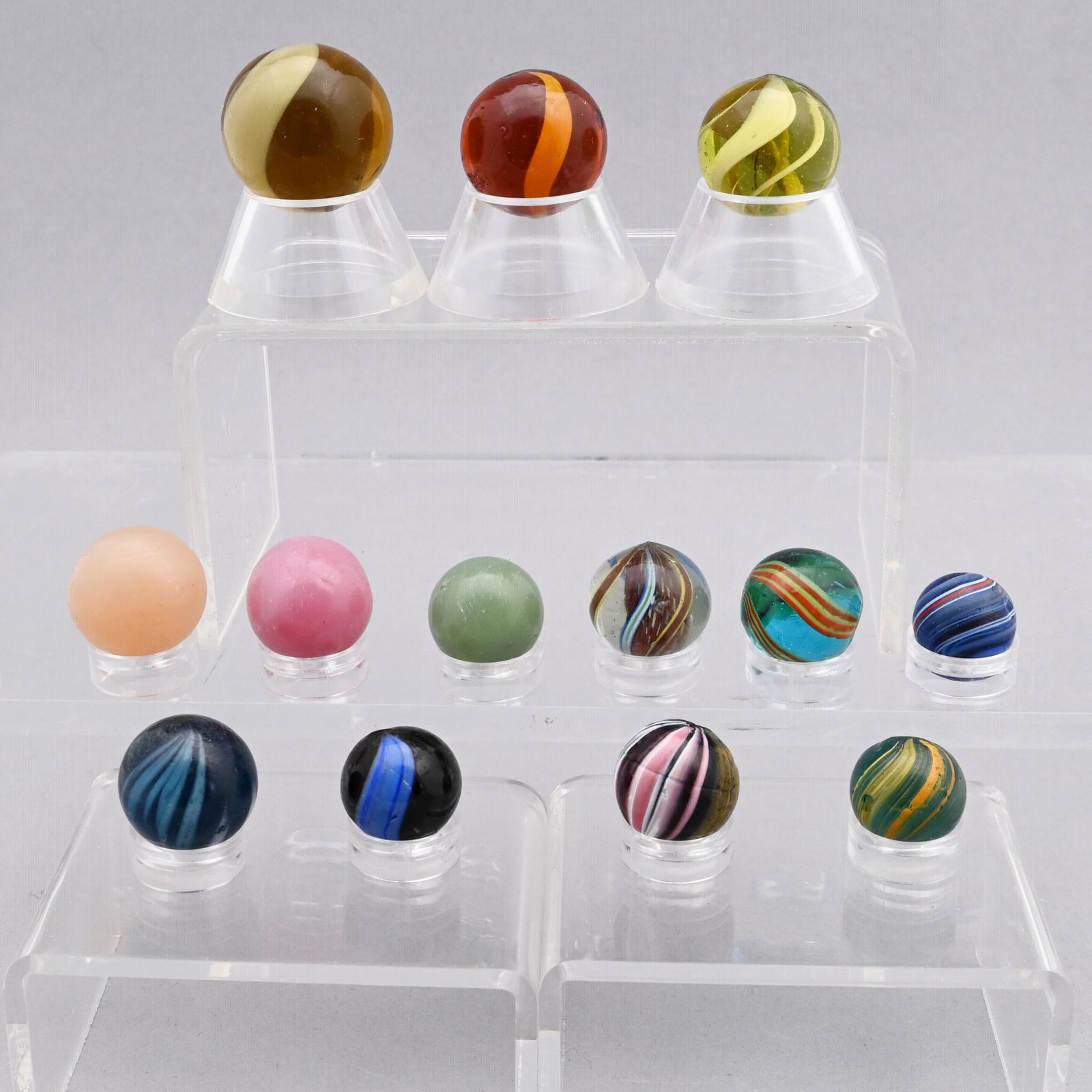 Thirteen Assorted Marbles: Comprising three Indians, three melon balls, three corn husks and three swirls. Approximate range of diam: 9/16 to 61/64 in.