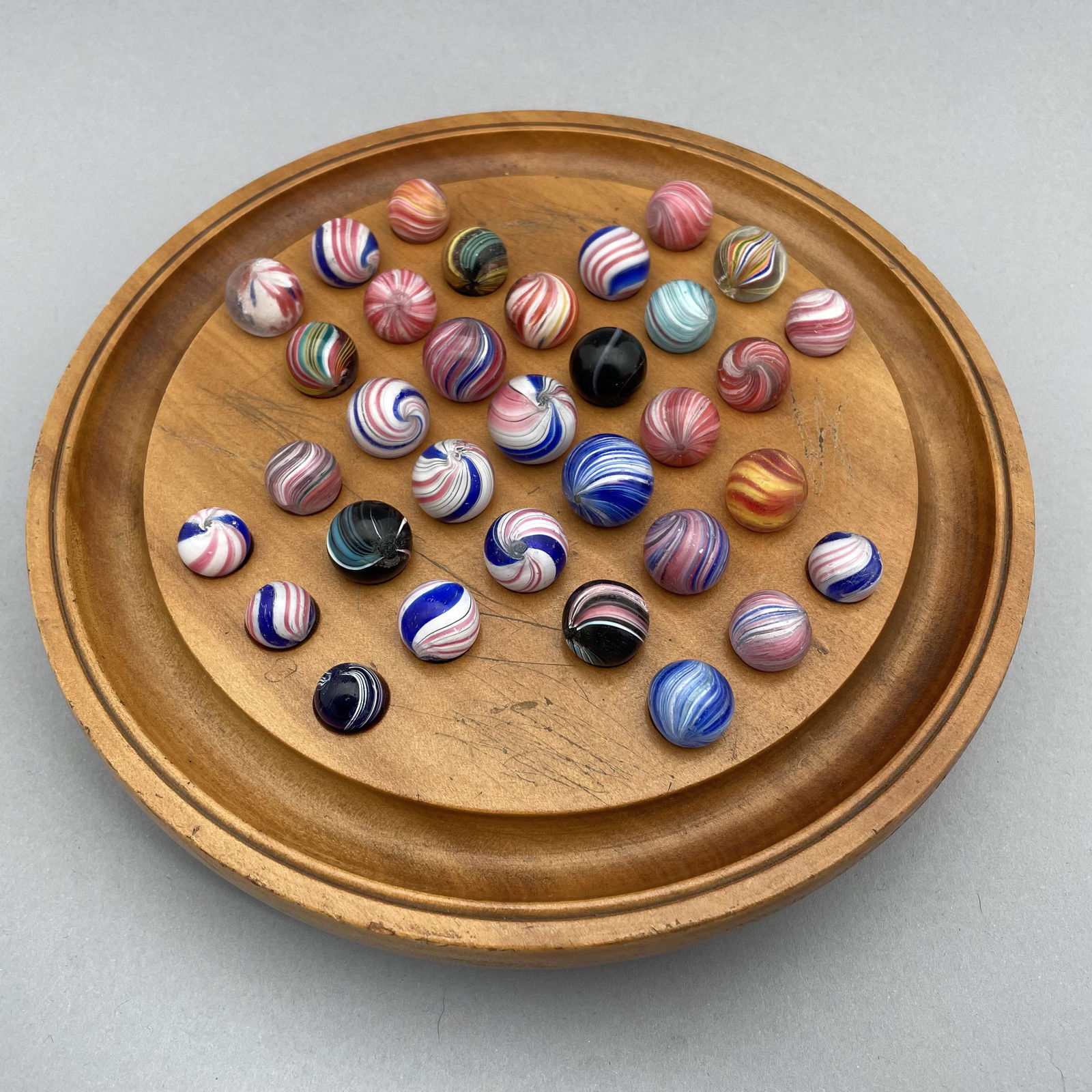General Grant Marble Board, Thirty-Three Marbles: The marbles handmade and comprising indians, onion skins, and peppermints. Approximate range of diam: 1/2 to 121/128 in. Board: 8.375 in., D: 1.625 in.