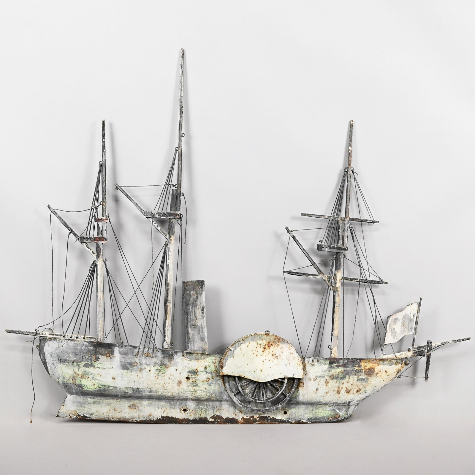 American Folk Art Sculpture of a Sidewheeler: The tin and iron three-masted vessel with traces of original white paint. H: 31.75 in., W: 39.5 in., D: 1 in.