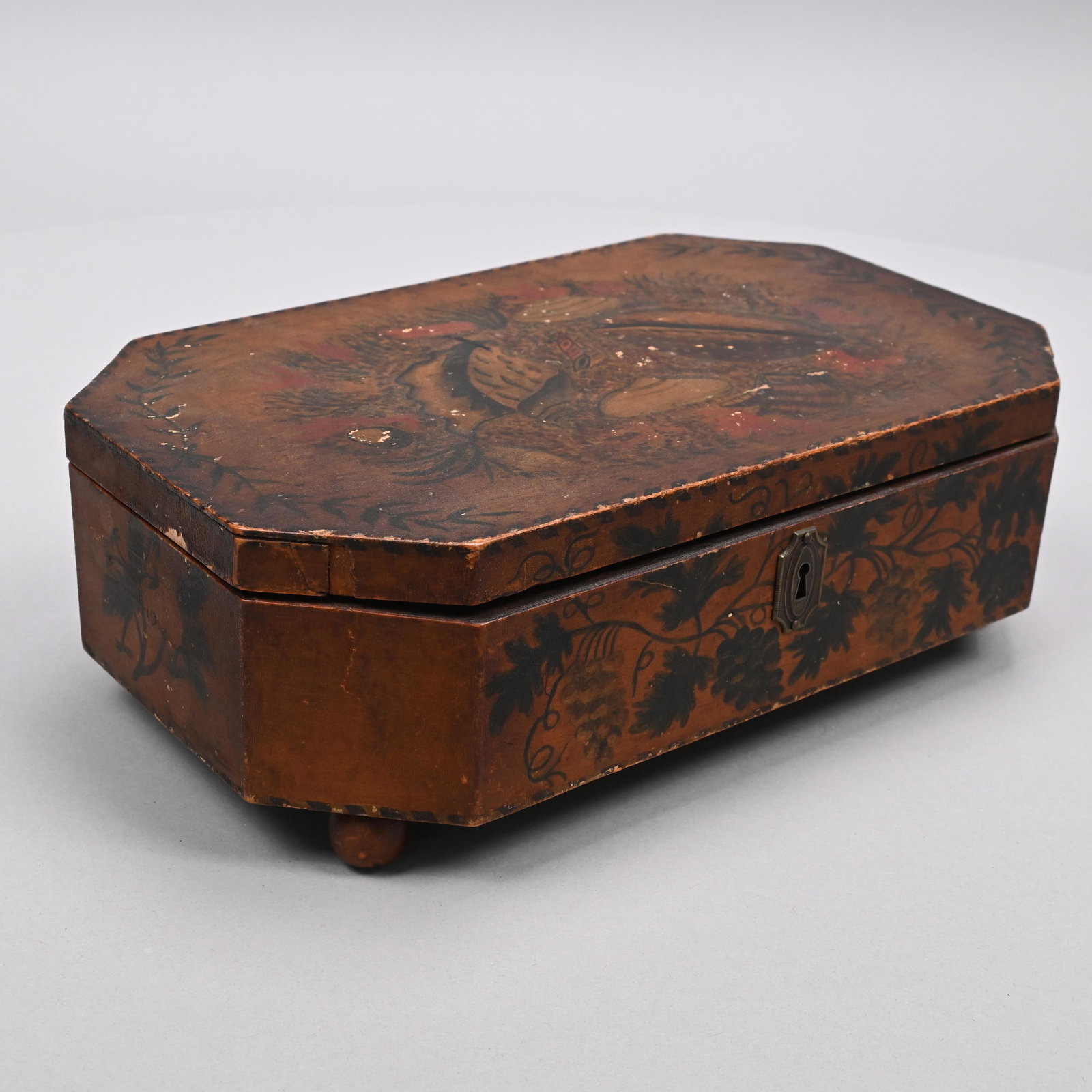 New England School Girl Paint-Decorated Sewing Box: Bird's-Eye Maple, Early Nineteenth Century. The elongated octagonal lid stencilled and painted with an arrangement of seashells and seaweed within a vine border, opening to reveal a divided foil-lined