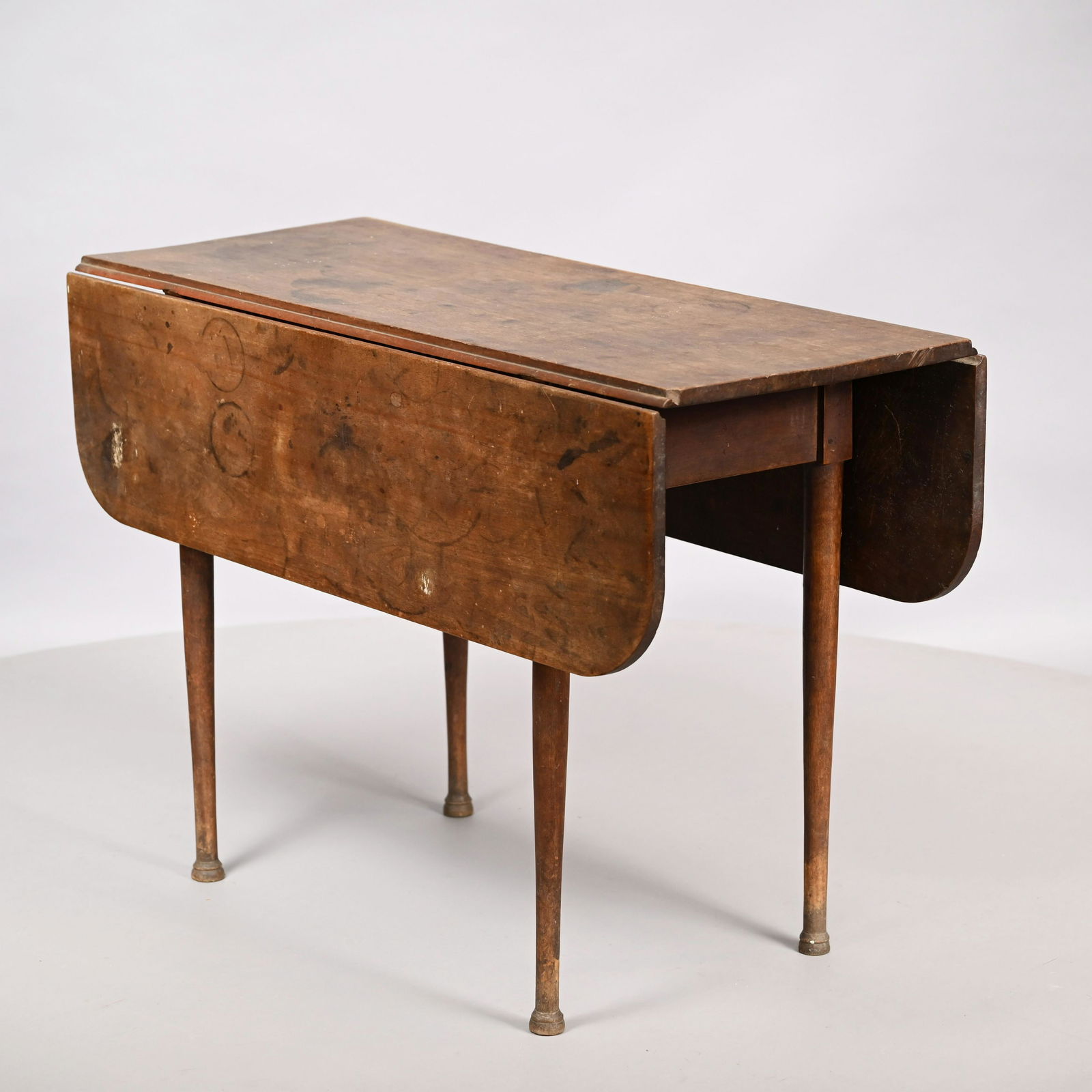 New England Birch Drop-Leaf Table: Early Nineteenth Century. The rectangular top with oblong drop leaves and wide overhang above a plain frieze, raised on turned tapered legs ending in penny feet. H: 28.75 in., W: (closed) 18.25 in., (