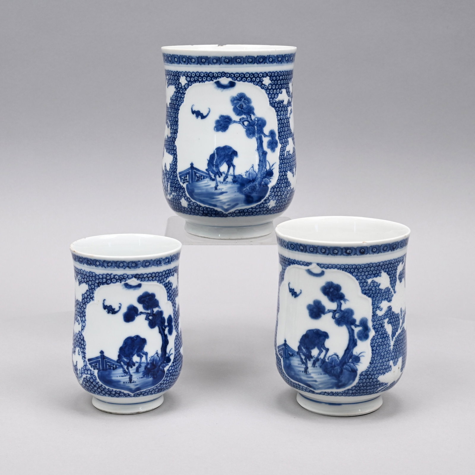 Three Chinese Export Porcelain Blue & White Canns: 1780-1805. Each painted on the front with bats hovering over a deer under a pine tree in a fenced garden, within a shaped panel with molded edge, the sides molded in white with peonies, butterflies an