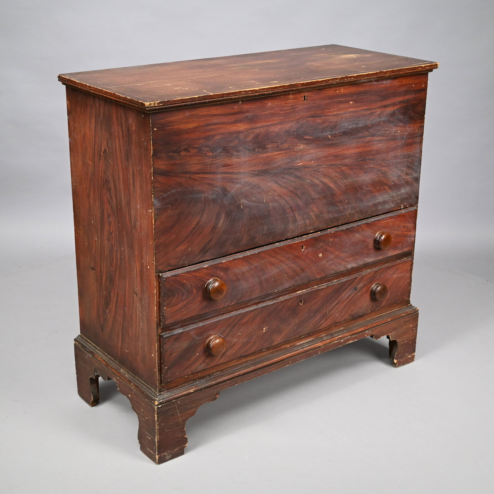 Chippendale Paint-Decorated Pine Blanket Chest: Early Nineteenth Century. In shades of brown paint, the rectangular top lifting to the compartment, above two drawers and raised on a bracket base. H: 36.75in., W: 37.5 in., D: 17.25 in.
