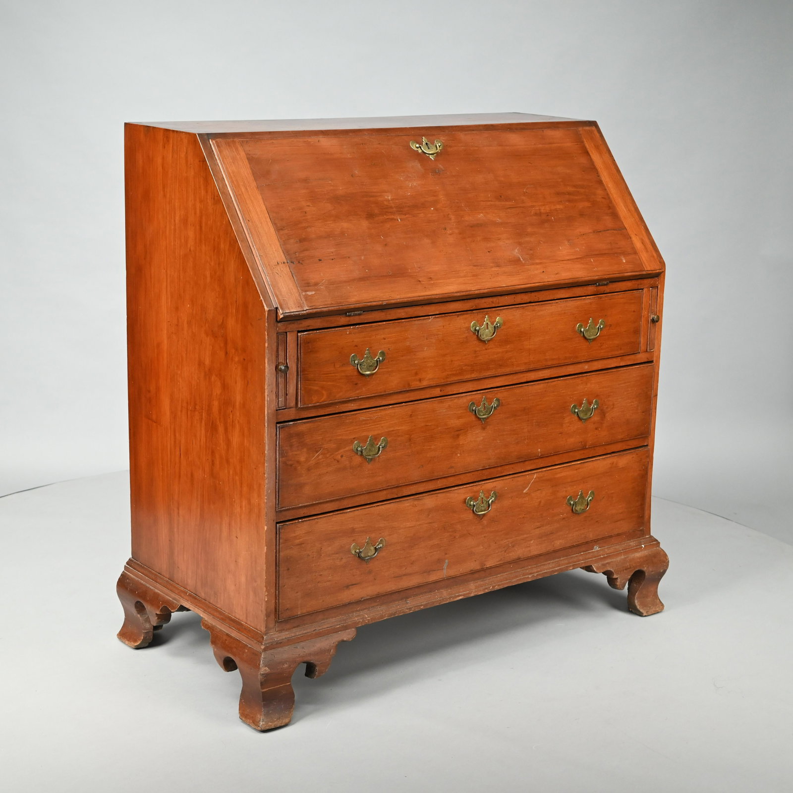 Chippendale Cherrywood Slant-Front Desk: Last Quarter Eighteenth Century. The rectangular top above a slant-front opening to the interior fitted with a series of drawers, cubbyholes and document drawers, above three molded graduated drawers,