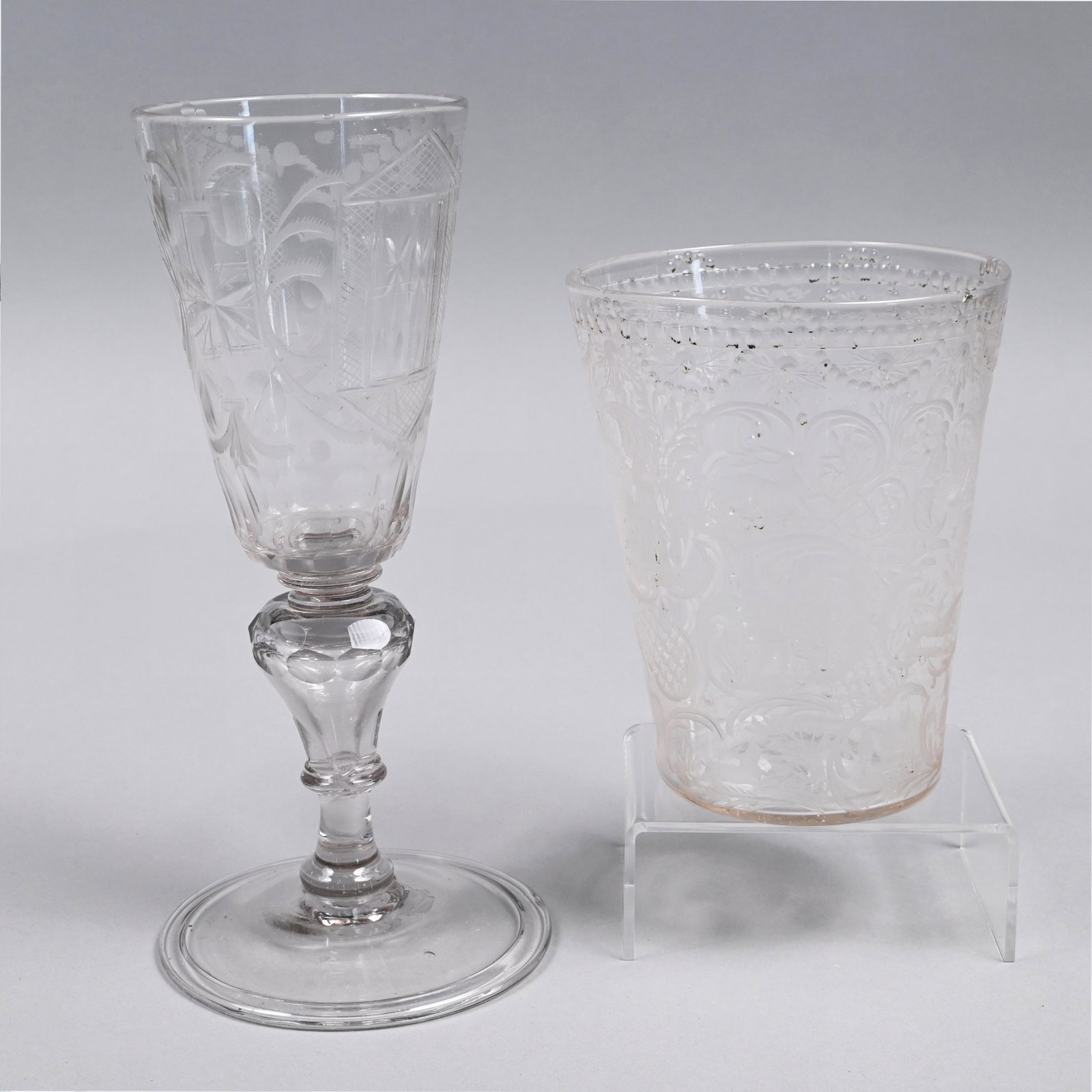 Two Bohemian Cut & Engraved Colorless Glass Wares: Nineteenth Century. Comprising a goblet, cut on two sides with a window alternating with plume, star and bullseye devices above a fluted border, the faceted knopped inverted pear-form standard above a