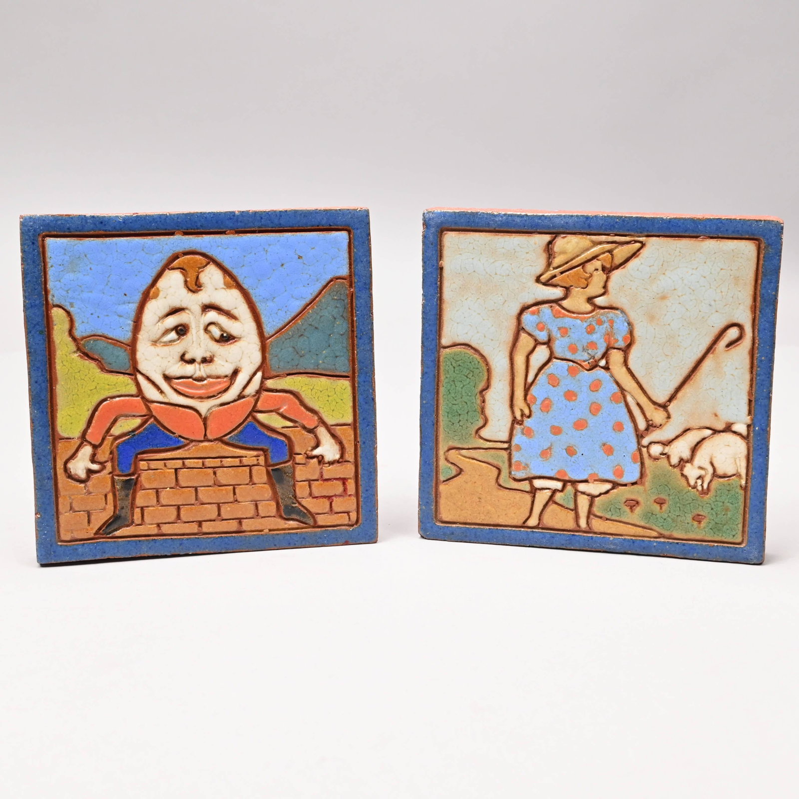 Pair of Nursery Rhyme Art Tiles, Twentieth Century: Pair of Nursery Rhyme Art Tiles, Twentieth Century. Depicting scenes from 'Humpty Dumpty' and 'Little Bo Peep,' each impressed "6383." H: 5.875 in., W: 5.875 in., D: .75 in.