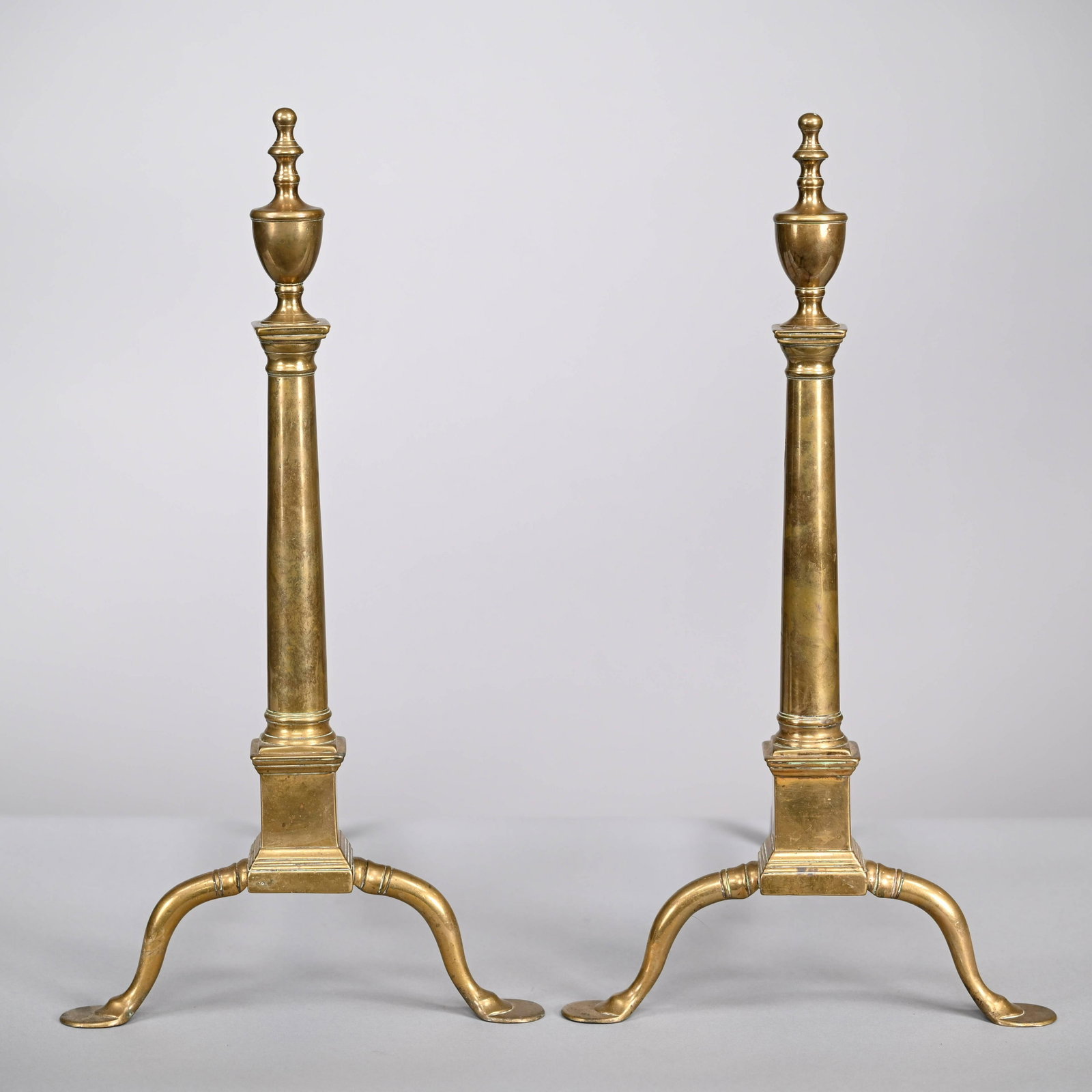 Pair of Federal Brass Penny-Foot Andirons: Pair of Federal Brass Penny-Foot Andirons, Early Nineteenth Century. Each columnar standard with urn finial above a pedestal base, raised on cabriole legs ending in penny feet. H: 23 in., W: 12.5 in.,