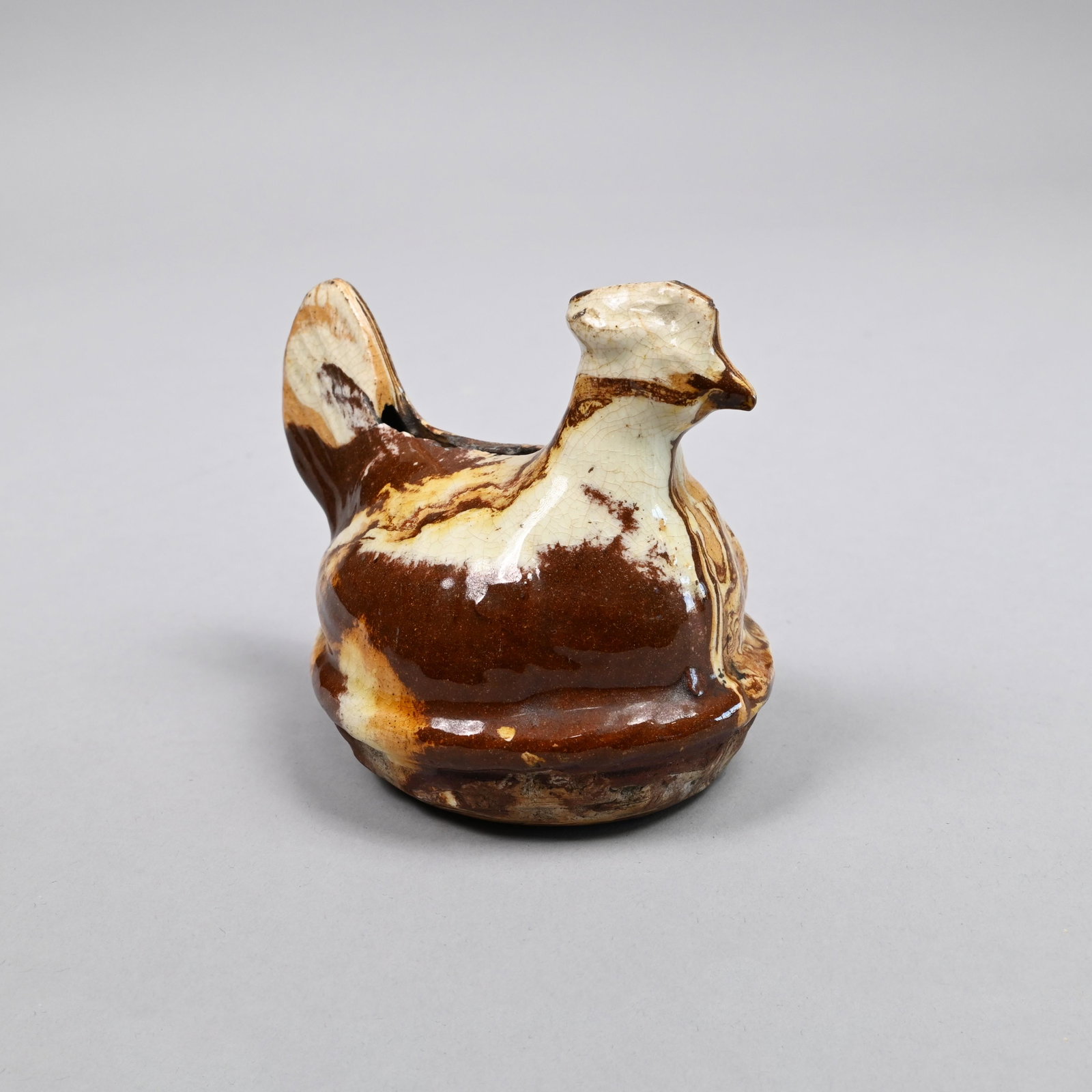 English Slip-Marbled Figural Hen Bank,19th Century: Modelled as a hen roosting on her nest, slip-marbled in shades of brown, yellow and white. H: 3.25 in., W: 3 in., D: 4.5 in.