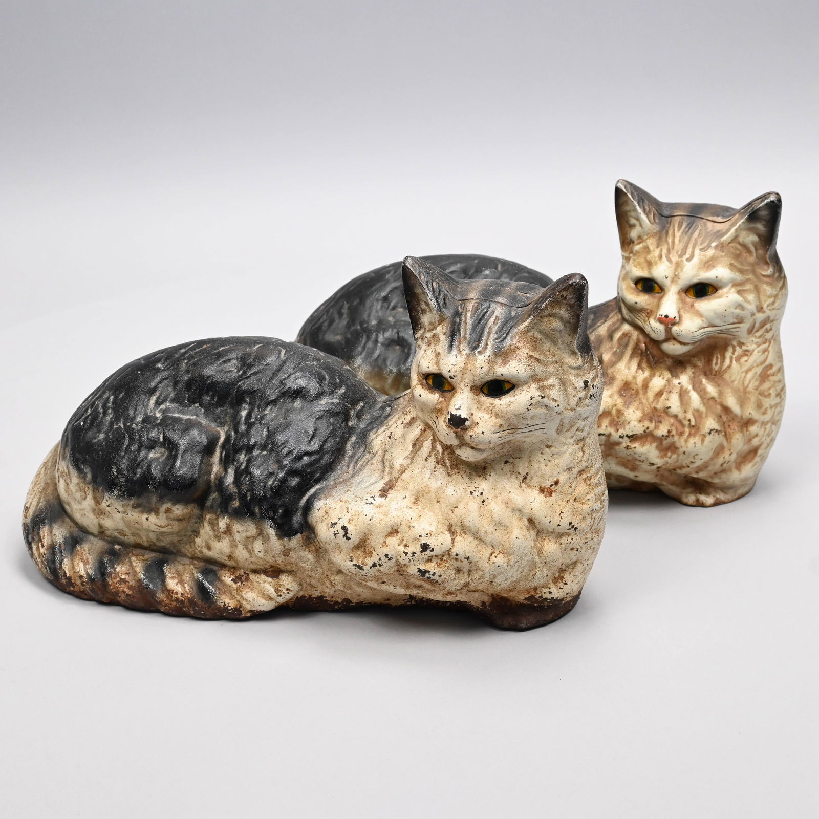 Pair of Painted Cast-Iron Recumbent Cat Doorstops: Pair of Painted Cast-Iron Recumbent Cat Doorstops, Twentieth Century. H: 7.25 in., W: 12.75 in., D: 5.5 in.