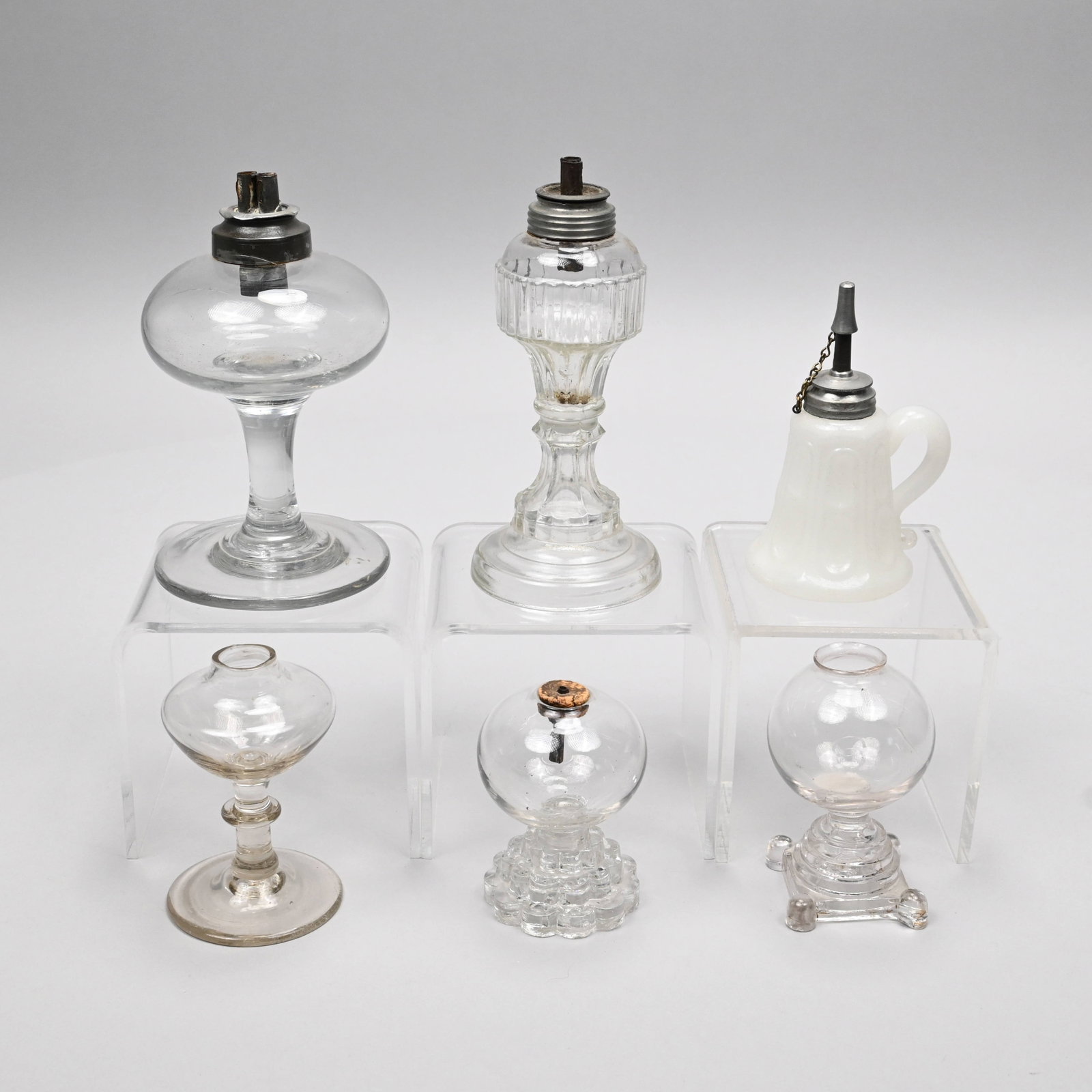 Six New England Free-Blown&Pressed Whale Oil Lamps: Five New England Free-Blown, Mold-Blown and Pressed Colorless Glass Whale Oil Lamps, and a Clambroth Finger Lamp, 1830-45. Comprising two free-blown, one with ogee font and knopped stem, the other wit