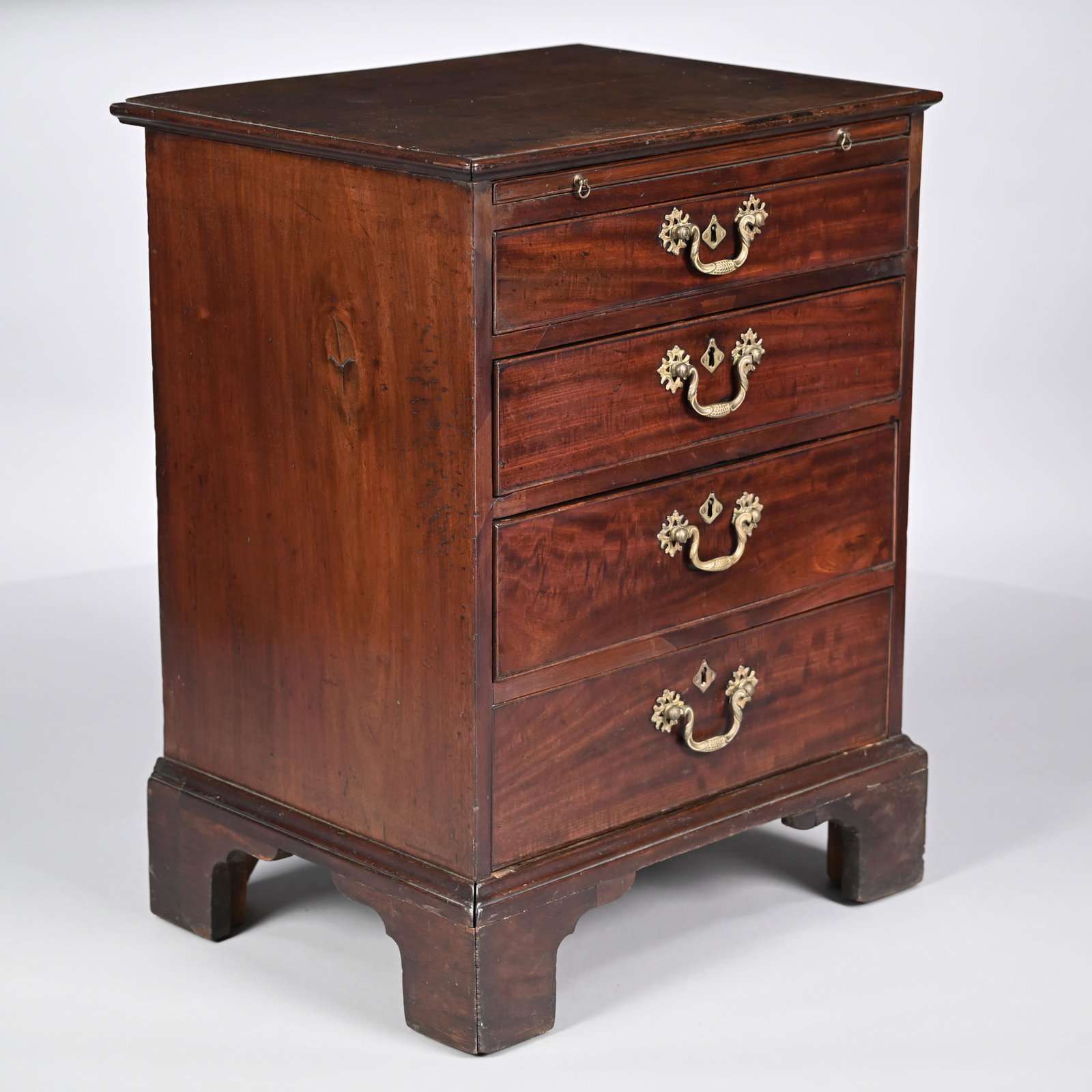 George III Mahogany Bachelor's Chest: George III Mahogany Bachelor's Chest. The rectangular top within an applied molded edge, above a brushing slide and four cockbeaded graduated drawers, raised on a bracket base. H: 30.5 in., W: 23.125 
