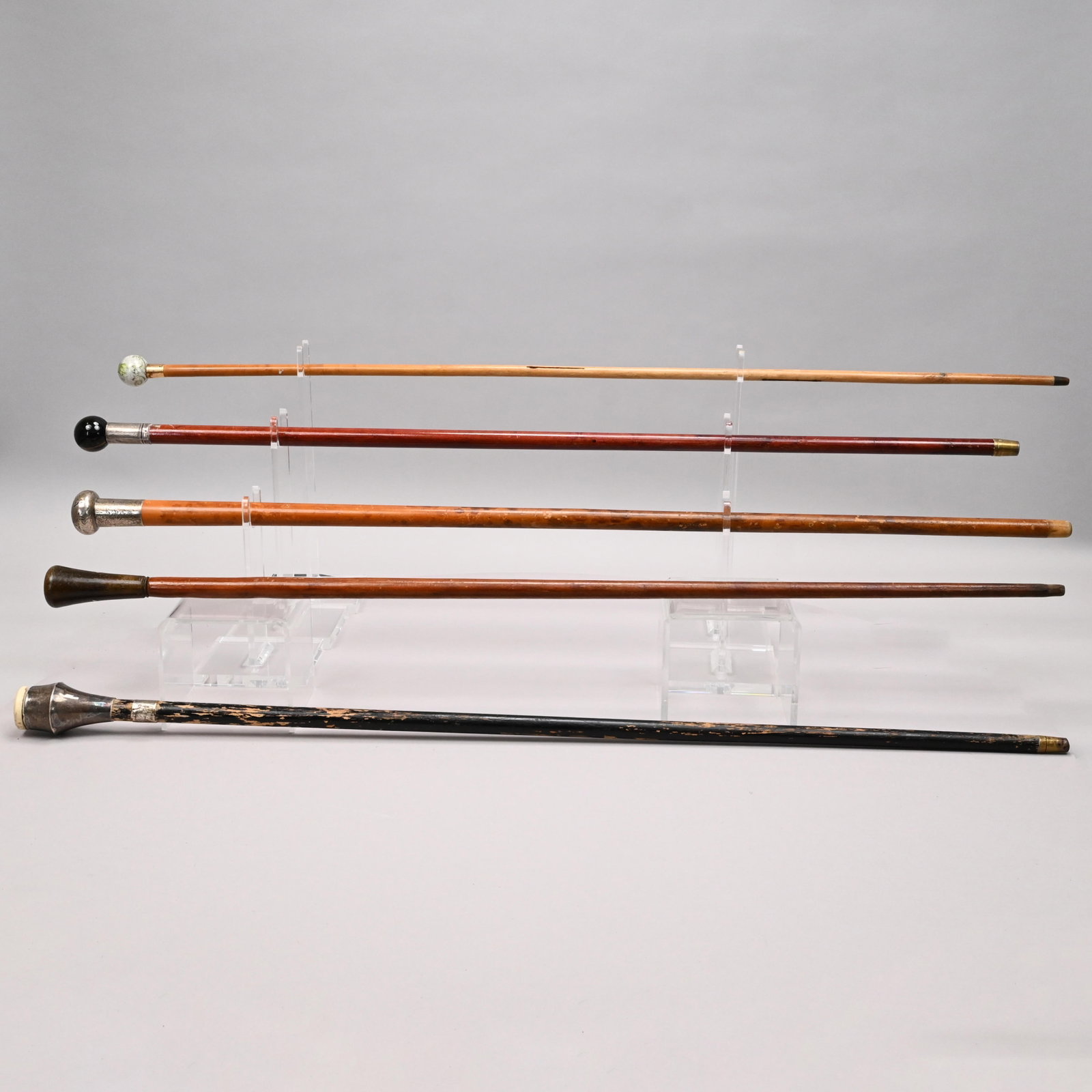 Five English and American Walking Sticks: Five English and American Walking Sticks, Late Nineteenth-Early Twentieth Century. Two mounted with glass grips, one with gold collar marked J*H," probably for Jonathan Howell; one stick with an engra
