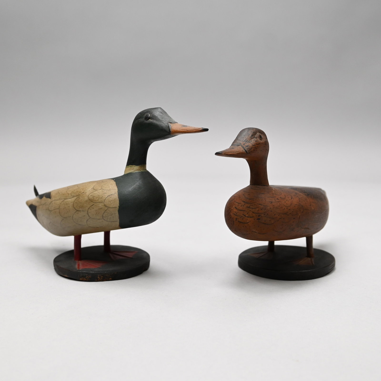 Pair of Carved and Paint-Decorated Mallards: Pair of Carved and Paint-Decorated Figures of a Drake and Hen Mallard, Twentieth Century. Each realistically painted, the male carved with an upturned tail feather, each pegged onto a circular wood ba
