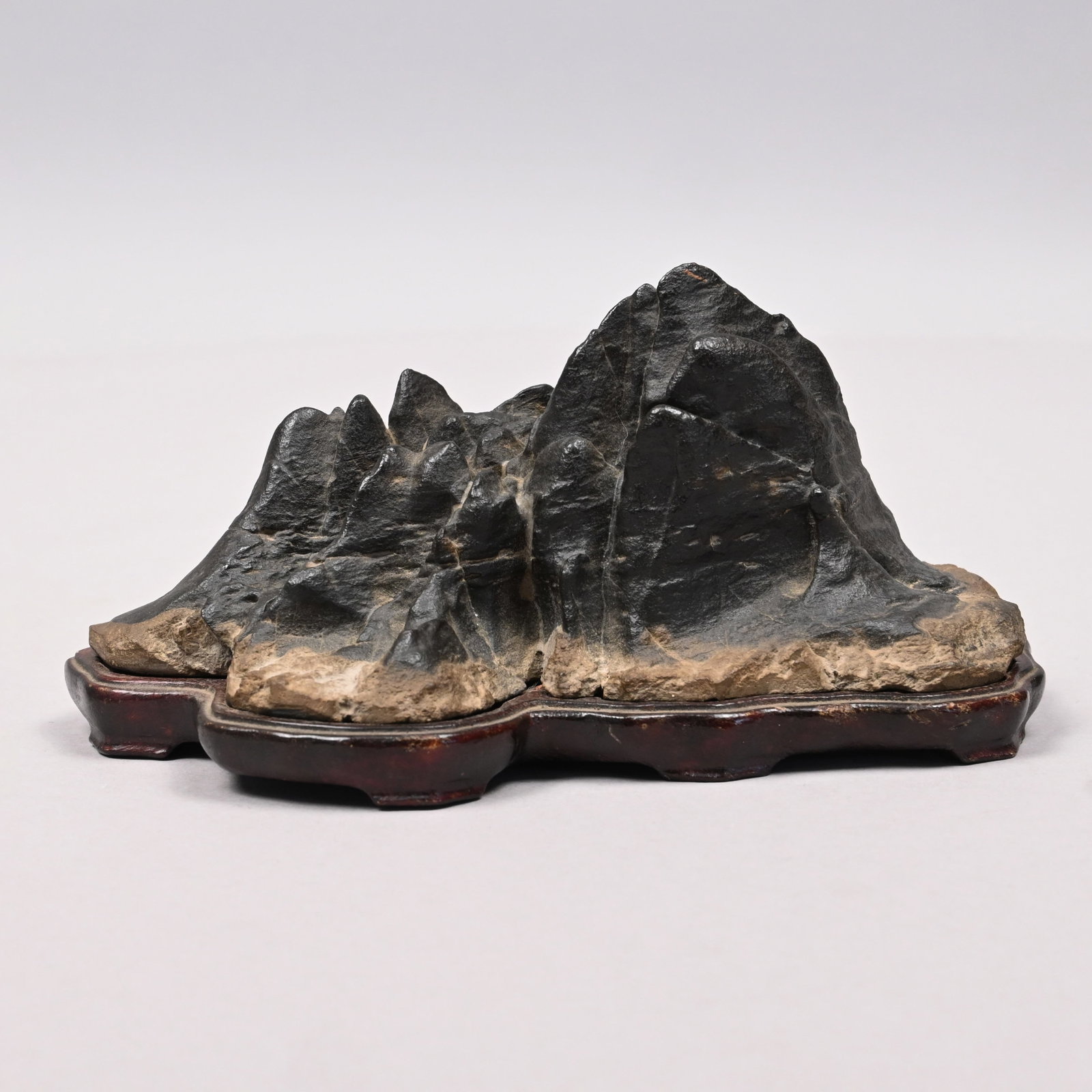 Chinese Grey Lingbi Mountain-Form Scholar's Rock: Chinese Grey Lingbi Mountain-Form Scholar's Rock or Gongshi. Of dark grey color, the angles of the rock lifting up to form a steep mountain range with deep and narrow clefts, with a conforming hardwoo