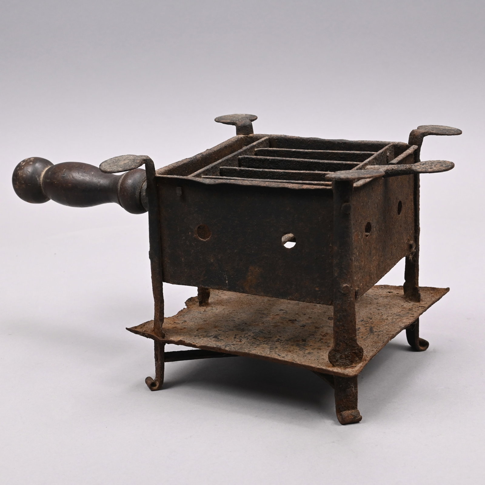 Early American Wrought-Iron Brazier: The hinged, lifting barred grill above a further grill below, above the sides of perforated sheet iron, mounted to each corner with an iron strut surmounted by a disc terminal, raised on scroll feet, 
