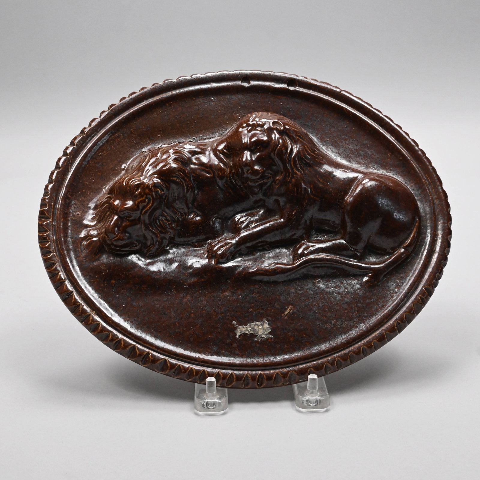 Staffordshire Saltglaze Stoneware Lion Plaque: Staffordshire Saltglaze Stoneware Lion Plaque, Late Eighteenth Century. Covered in dark brown glaze, and molded with a pair of napping lions. H: 8 in., W: 9.875 in., D: 1.625 in.