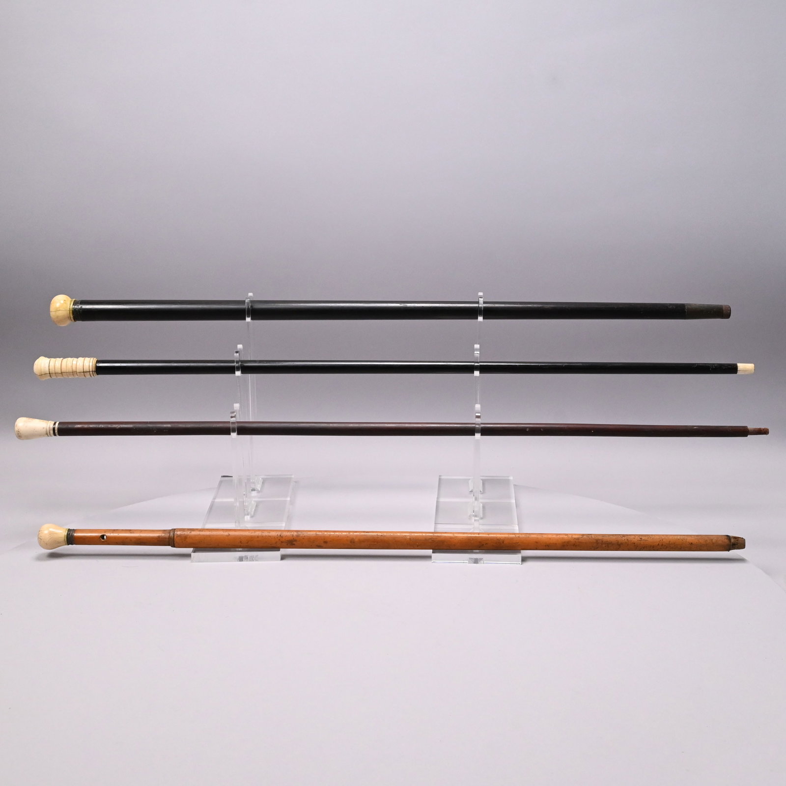 Four Scrimshaw Walking Sticks: Four Scrimshaw Whalebone and Wood Walking Sticks, Nineteenth Century. The top of one walking stick grip fitted with a circular abalone mount, one walking stick with bobbin-turned grip and whalebone ti