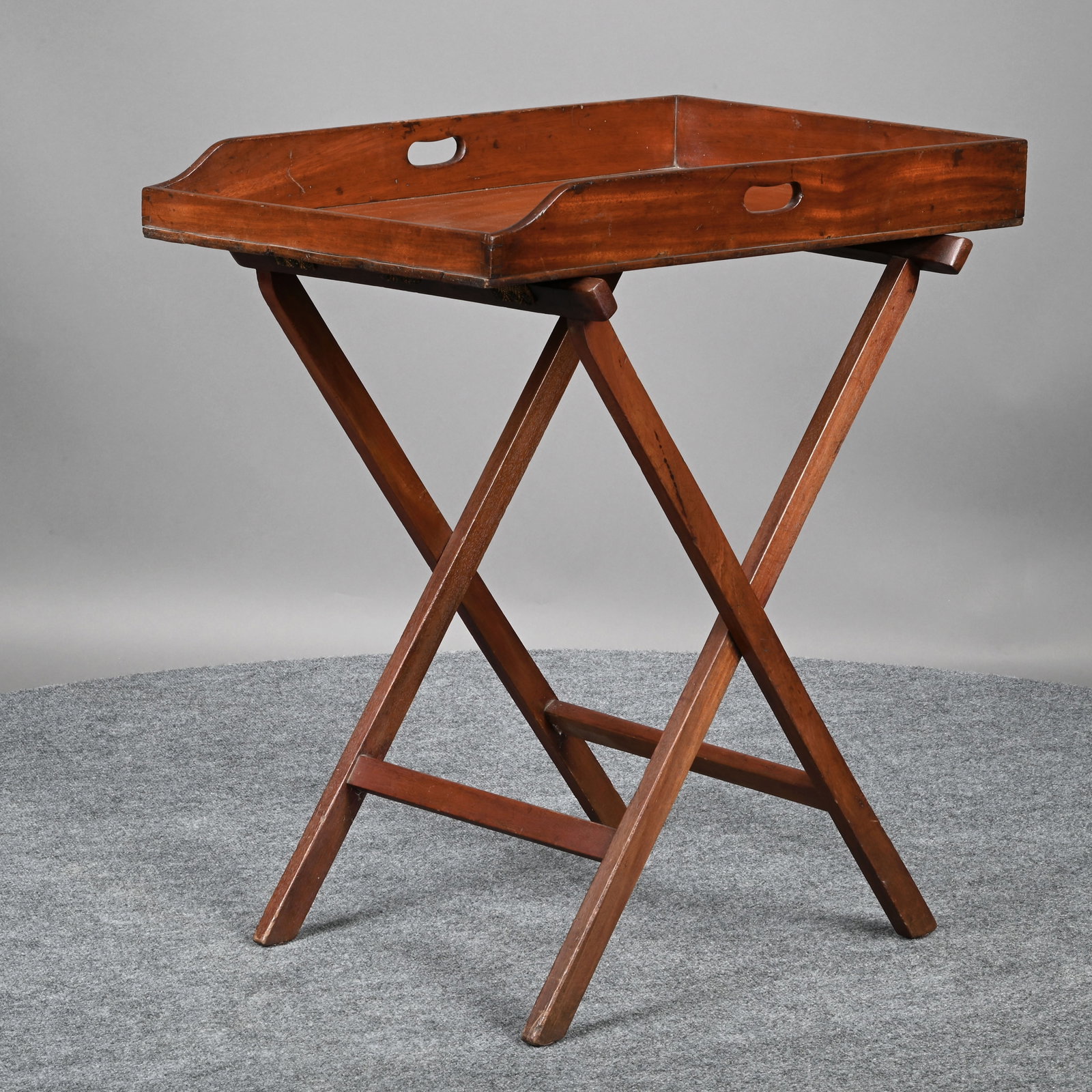 Butler's Mahogany Tray on Stand: Butler's Mahogany Tray on Stand. The rectangular tray with pierced hand holds, raised on a later X-form stretcher base. H: 32.625 in., W: 29.625 in., D: 19.25 in.