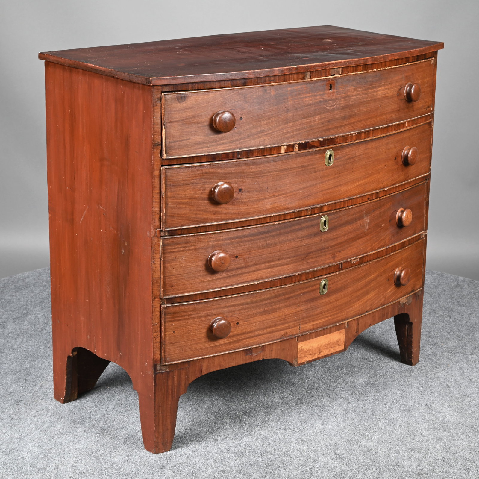 Coastal New Hampshire Federal Chest of Drawers: Coastal New Hampshire Federal Mahogany Chest of Drawers, Early Nineteenth Century. The bow-front top above four cockbeaded drawers and a serpentine apron veneered with a drop birch panel, raised on br