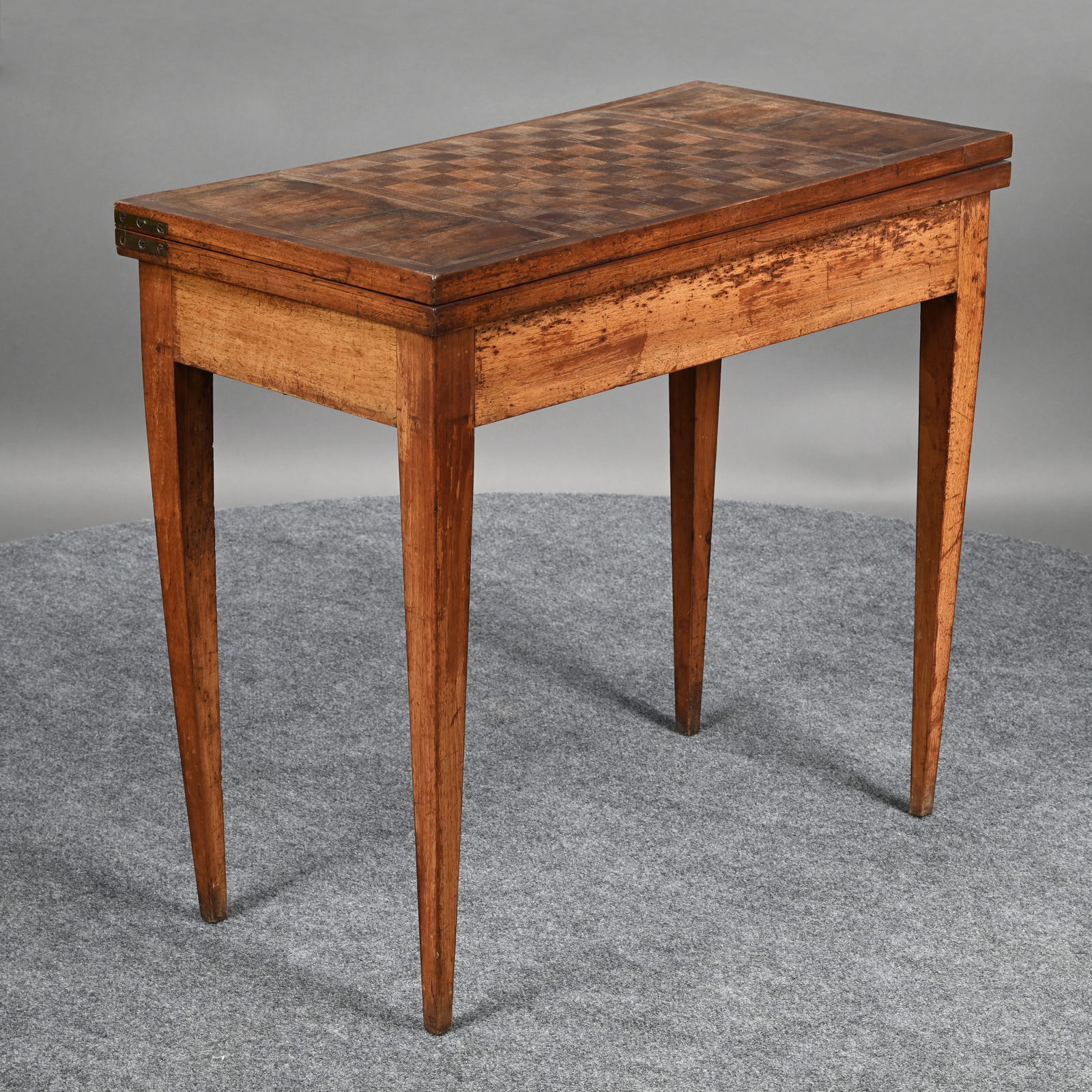 French Louis XVI Inlaid Mahogany Games Table: The parquetry checkerboard top opening to a baize-lined playing surface, swivelling above a plain frieze and raised on square tapered legs. H: 29 in., W: 32 in., D: 16.5 in. (Closed), 33 in. (Open)