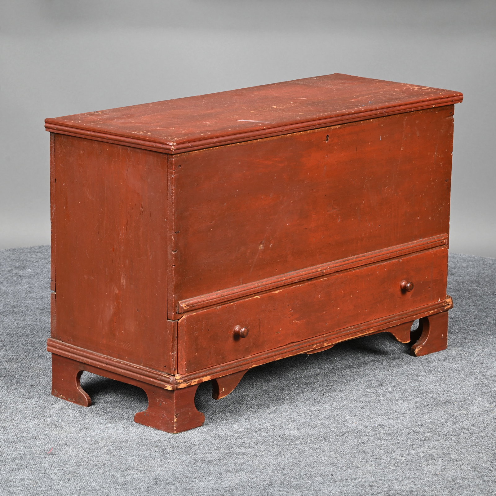 Pine Blanket Chest in Dark Red Paint: Pine Blanket Chest in Dark Red Paint. The rectangular top with applied edges opening to the interior, over one working drawer, raised on later shaped bracket feet. H: 22 in., W: 33.25 in., D: 13.75 in