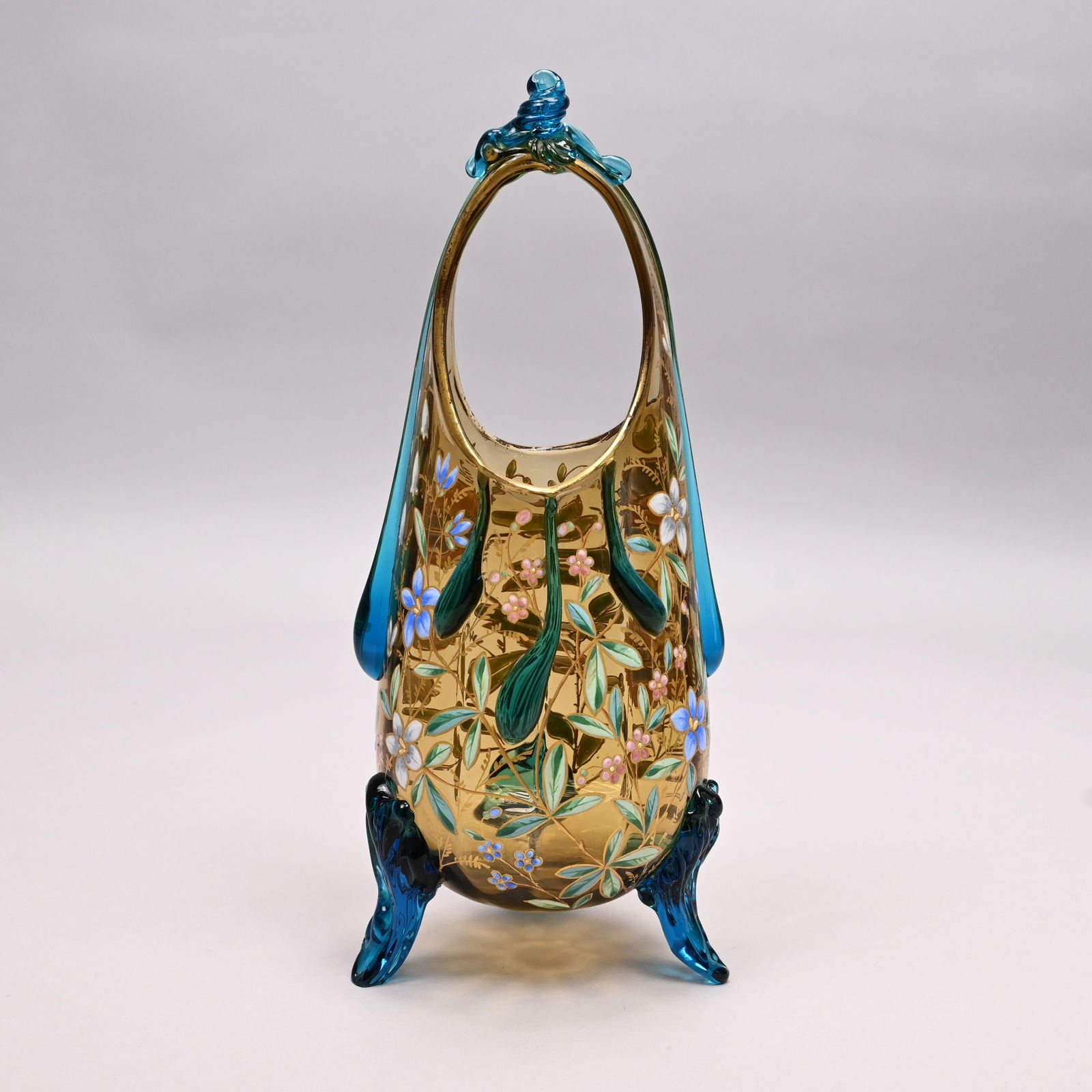 Bohemian Enamelled Glass Vase, Ludwig Moser & Sons: Bohemian Enamelled Glass Basket Vase, Ludwig Moser & Sons, Karlsbad, 1870 - 1938. The elongated basket in pale amber glass, the loop handle applied with a blue swirled bow with long ribbon prunts, thr
