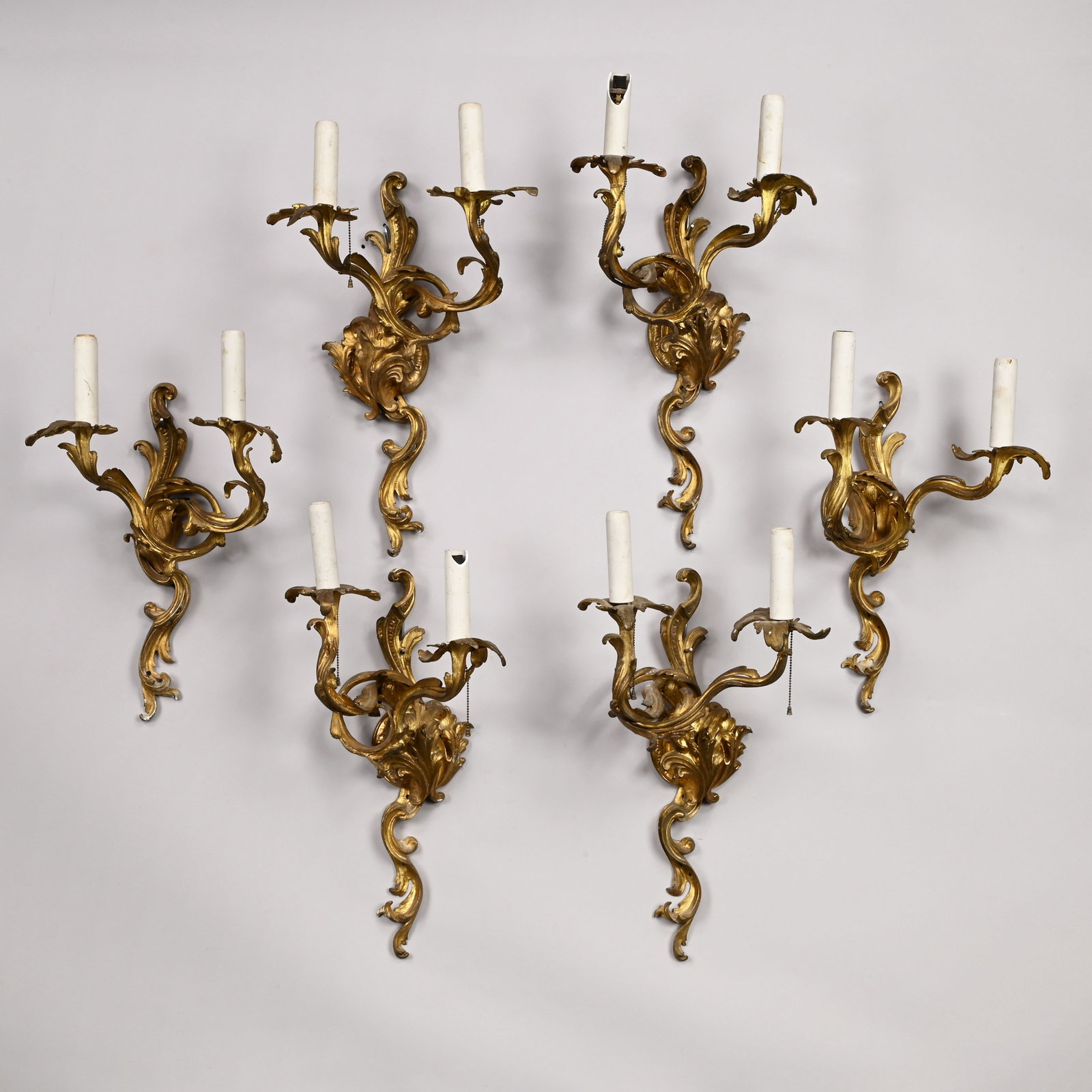 Six Louis XV Style Gilt-Bronze Bras de Lumiere: Six Louis XV Style Gilt-Bronze Two-Light Bras de Lumiere, Late Nineteenth Century. Comprising a set of four and a pair, each volute standard cast with acanthus leaves, issuing two entwined arms ending