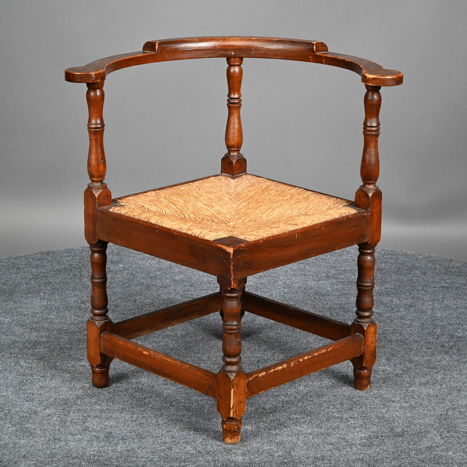 William and Mary Pine and Poplar Roundabout Chair: William and Mary Pine and Poplar Roundabout/ Corner Chair. The curved crest rail ending in circular arm rests, on ring-turned columnar supports, the square rush seat raised on ring-turned columnar leg