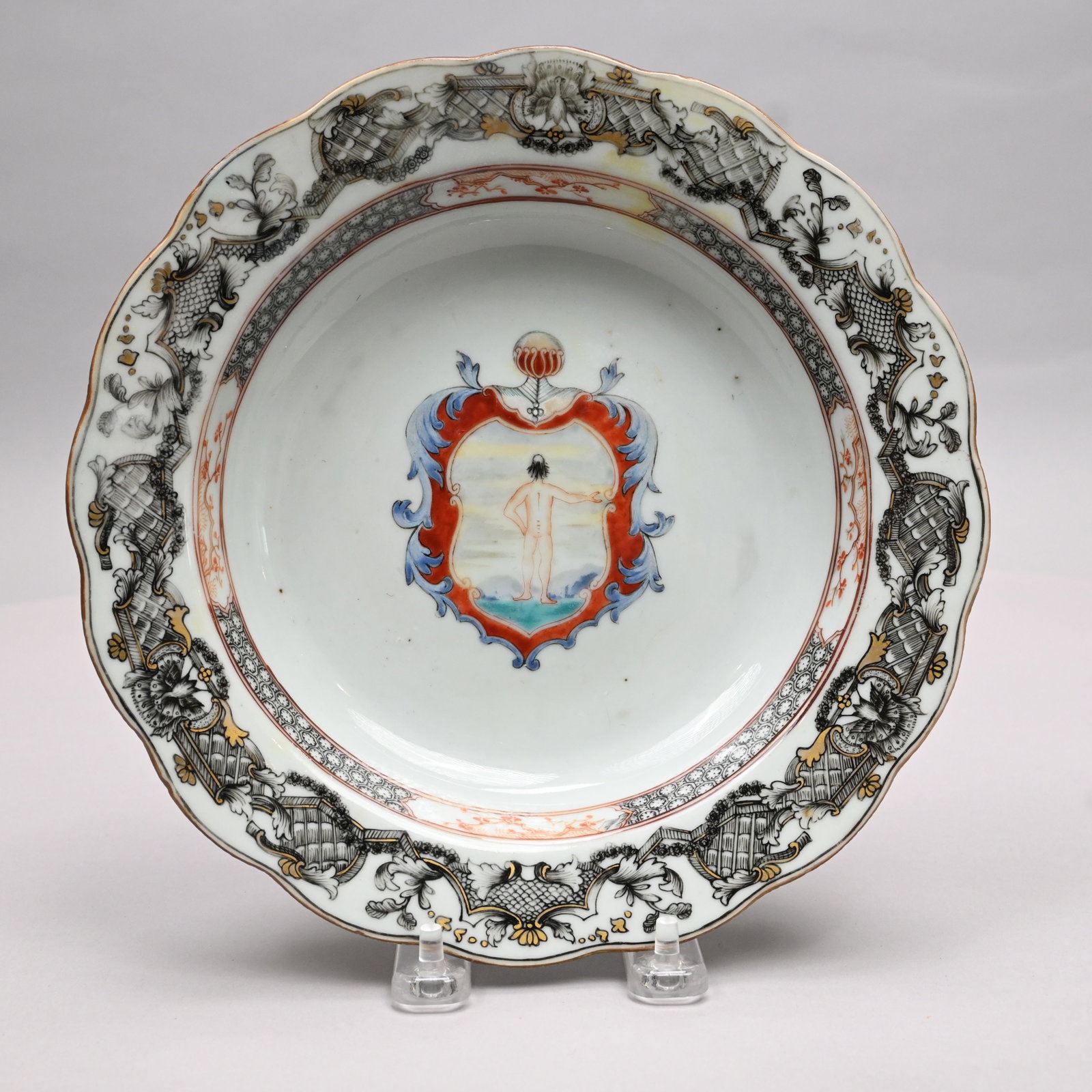 Chinese Export Porcelain Armorial Soup Plate: Chinese Export Porcelain Armorial Soup Plate, Circa 1750. Painted in iron-red, blue, turquoise and black enamels with a shield enclosing the view of a nude boy from the back with one arm outstretched,