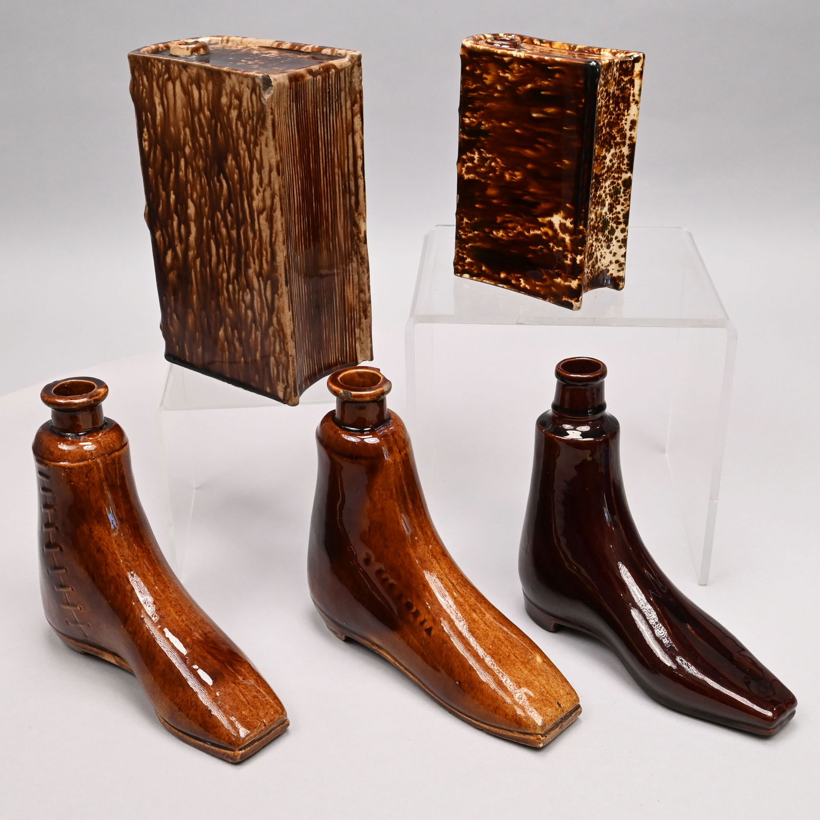 Five Rockingham-Glazed Pottery Flasks: Five Rockingham-Glazed Pottery Flasks, Mid-Late Nineteenth Century. Comprising a pint book flask, Bennington, Vermont, 1849-58, impressed "DEPARTED SPIRITS" on the spine; an unmarked book flask, and t