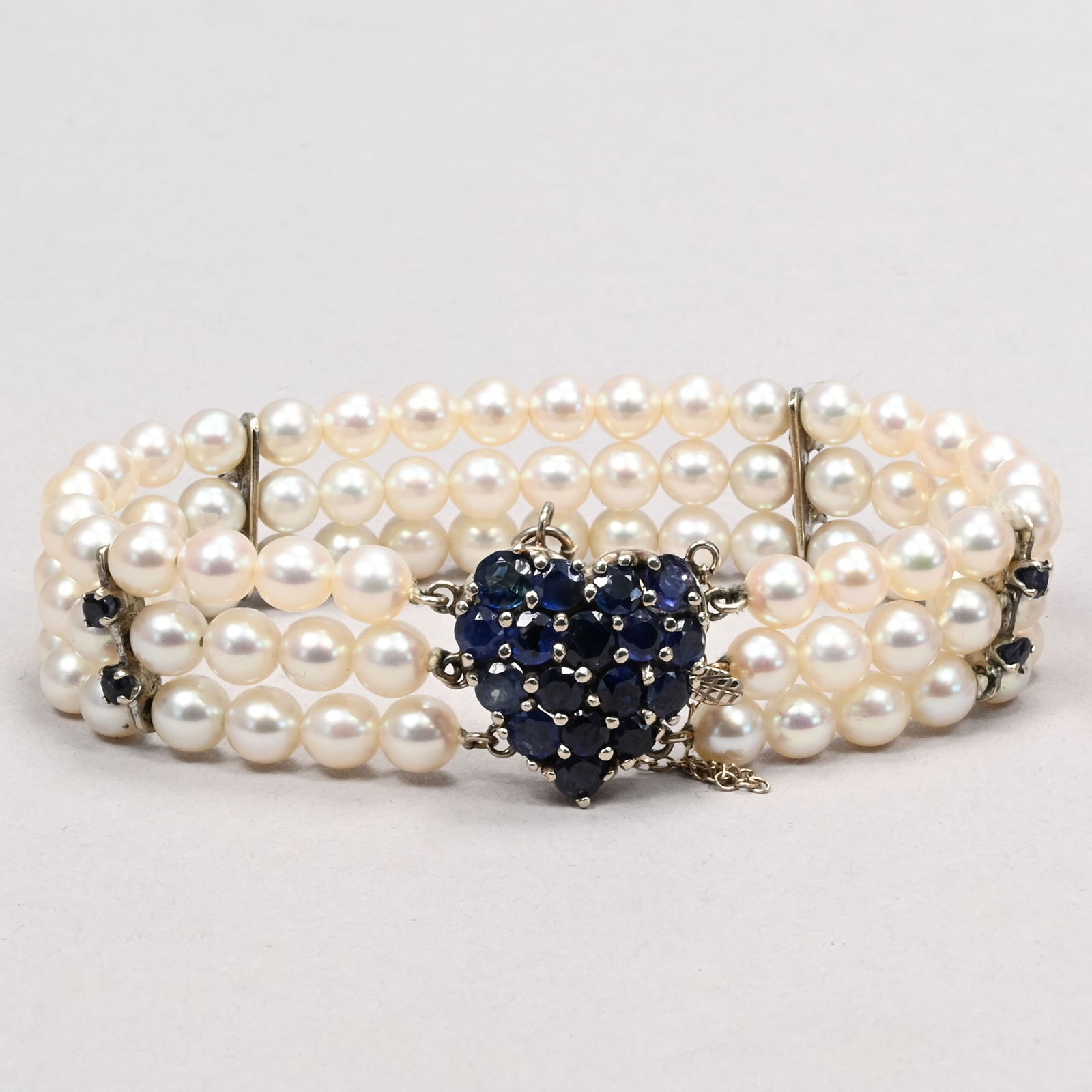 14k White Gold, Sapphire and Pearl Bracelet: 14k White Gold, Sapphire and Pearl Bracelet. Three stands of 2 mm pearls, the heart-shaped clasp set with sapphires, marked "14k".L: 6.5 in.