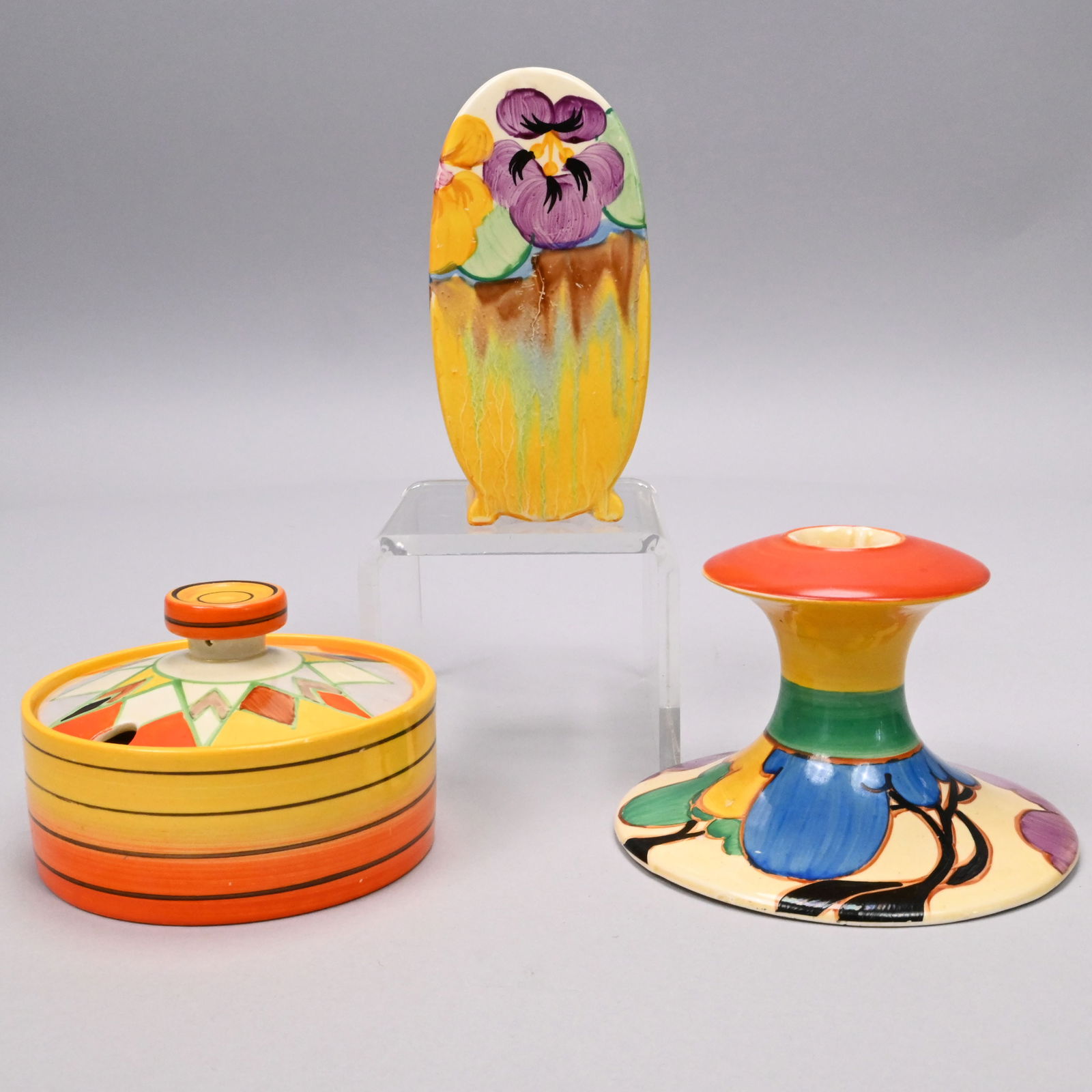 Three Clarice Cliff Bizarre & Fantasque Wares: Three Clarice Cliff Bizarre and Fantasque Tablewares, Newport Pottery, 1931-1937. Comprising a Bizarre 'Pansies' Bonjour shape muffineer or sugar sifter, partly stamped "Bizarre/ MADE IN ENGLAND;" a