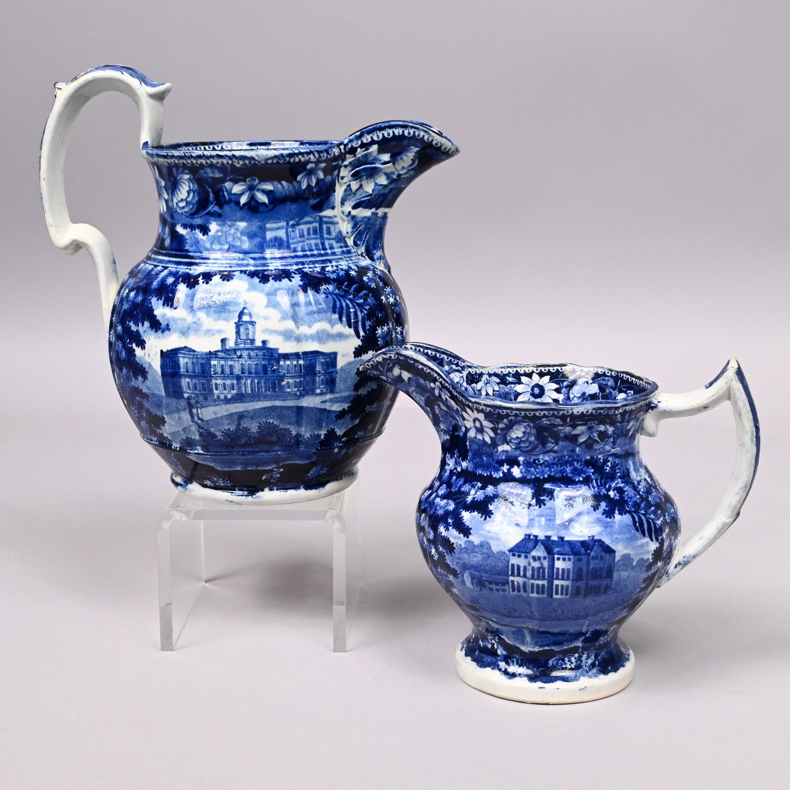 'Flowers & Foliage' Series, 2 Staffordshire Pitche: 'Flowers and Foliage' Series, Two Staffordshire Blue Transfer-Printed Pitchers, James & Ralph Clews, 1818-1836. The first pitcher printed on one side with an unidentified three story building with two
