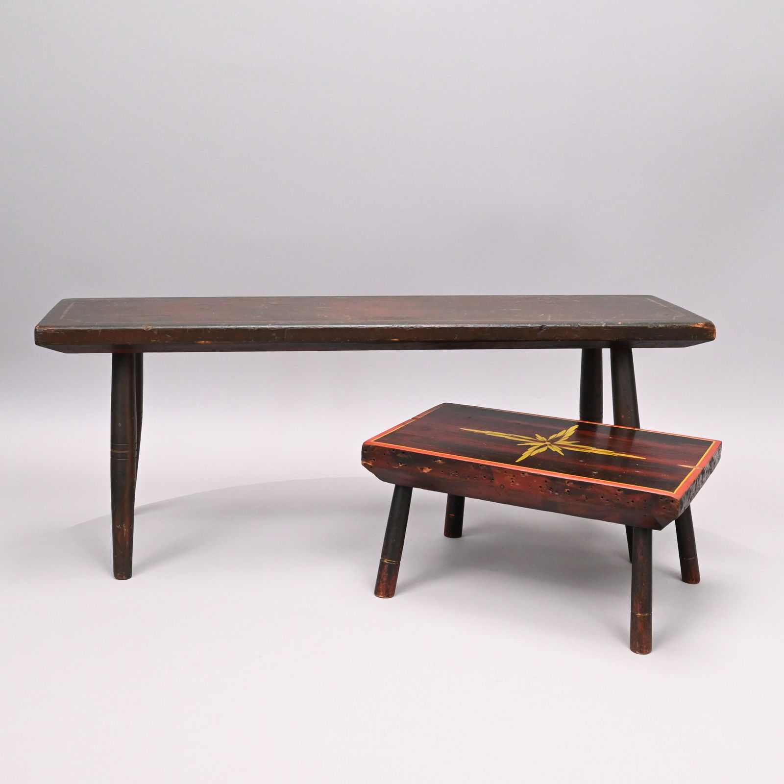 Two Paint-Decorated Wood Cricket Stools: Two Paint-Decorated Wood Cricket Stools. Each rectangular on turned legs and painted to simulate rosewood, the first stencilled with a foliate star in yellow-green, each top within conforming borders.