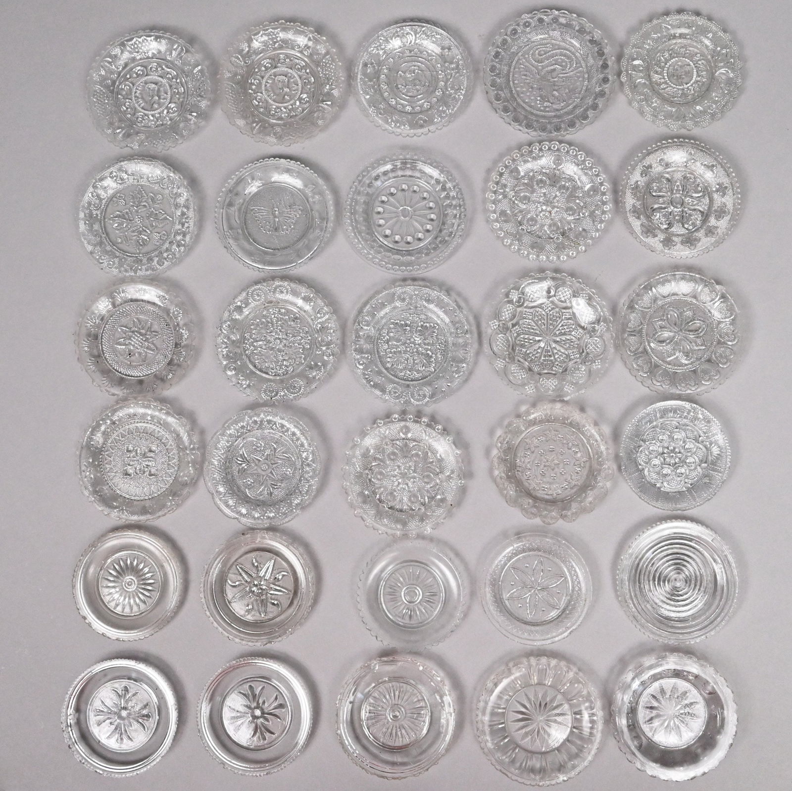 Grp Eastern & MidwesternColorless Glass Cup Plates: Group of Eastern and Midwestern Pressed Colorless Glass Cup Plates, Early 19th Century. Comprising an Eagle cup plate, R.B. Curling & Sons, Fort Pitt Glass Works, Pittsburgh, Pennsylvania, 1830-1845