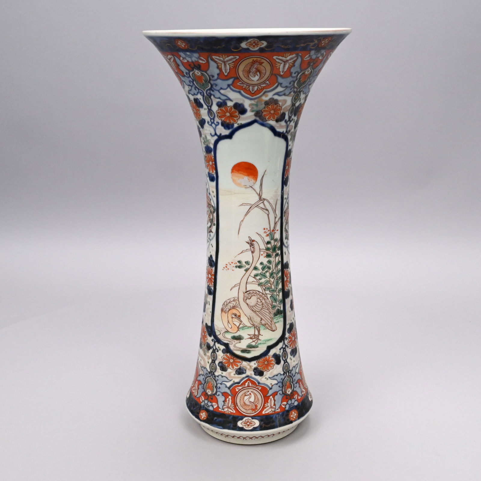Japanese Arita Imari Porcelain Trumpet Vase: Japanese Arita Imari Porcelain Trumpet Vase, Edo/ Meiji Eras. Painted with two elongated panels of a pair of cranes in a landscape with setting sun, joined by shaped panels of phoenix and all