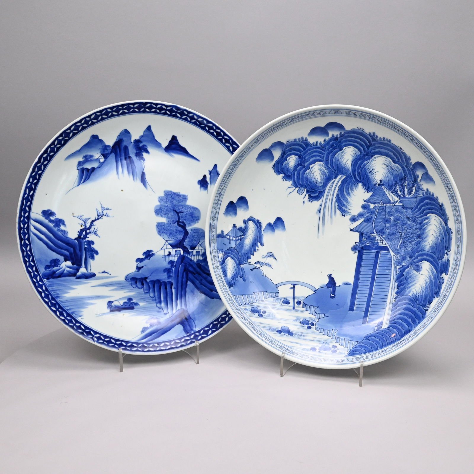 Two Japanese Blue and White Porcelain Chargers: Two Japanese Blue and White Porcelain Chargers or Low Bowl, Meiji Era. The first depicting a house with louvered screen and a figure on the banks of a stream crossed by a bridge, seal mark in