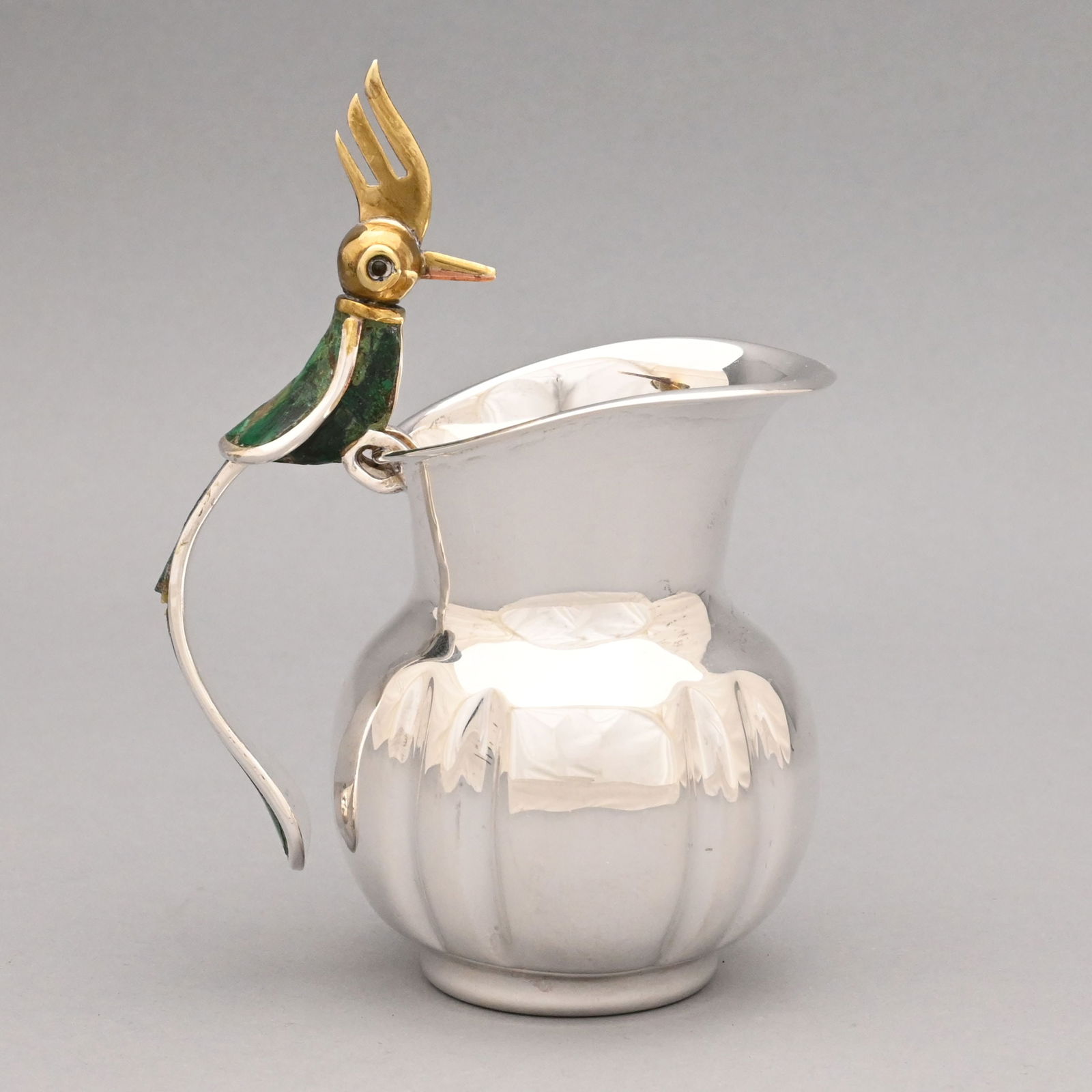 Mexican Silver 'Bird of Paradise' Jug,Los Castillo: Mexican Sterling Silver Modernist 'Bird of Paradise' Cream Jug, Los Castillo, Taxco, 1970s. The pitcher of fluted baluster form, the handle a figure of a bird with glass eyes, brass crest, head and