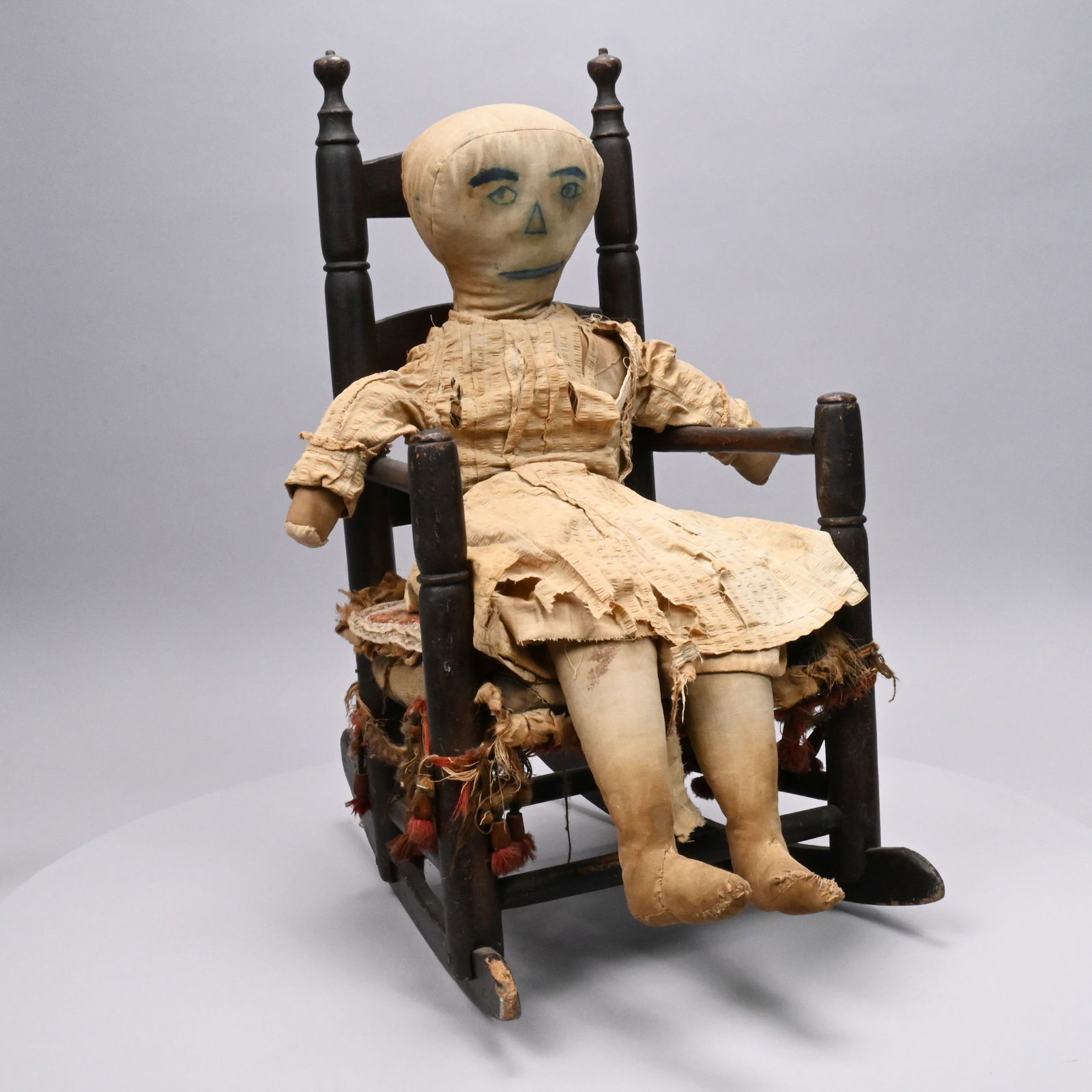 Folk Art Fabric Doll and Children's Rocking Chair: Folk Art Fabric Doll and an American Children's Rocking Chair, 19th Century. The chair in the original dark finish, the needlepoint cushion worked with a spray of roses, with a cotton patchwork