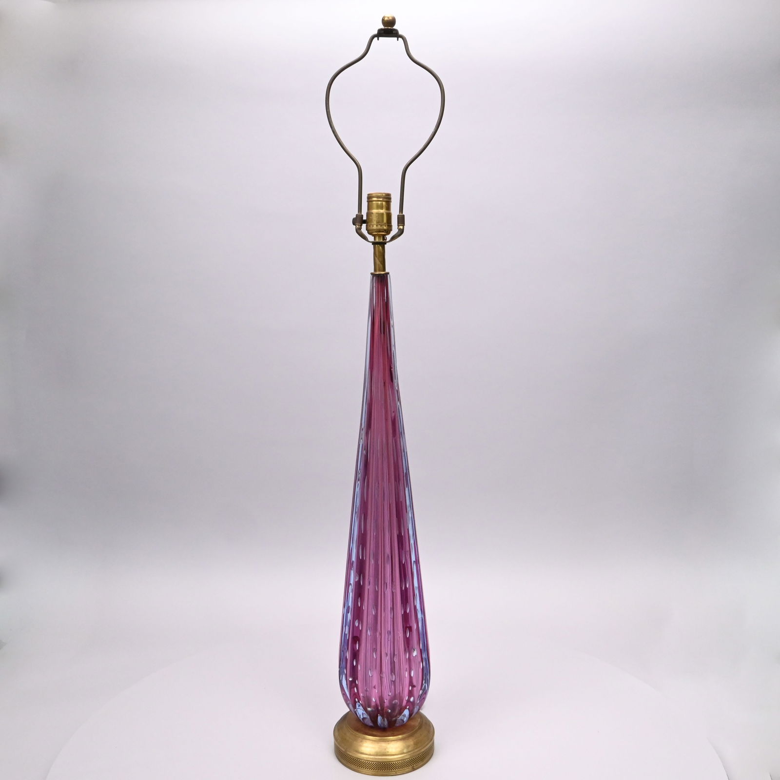 Murano Glass Controlled Bubble Table Lamp Base: Murano Glass Controlled Bubble Table Lamp Base, Mid-Century Modern. In cranberry glass, of tapered baluster deeply ribbed form, enclosing rows of controlled bubbles, on a brass base.H: 30 in. (to top