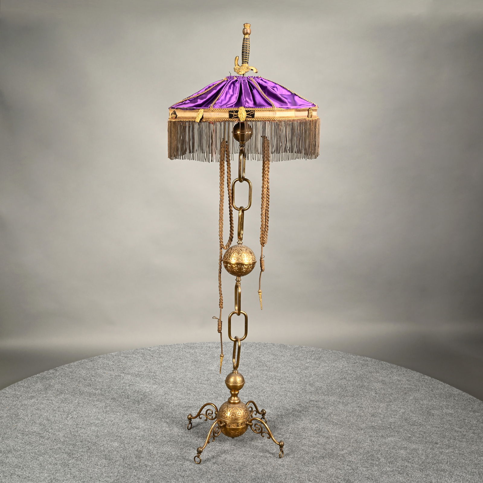 American Fraternal IOOF Lodge Brass Floor Lamp: American Fraternal Independent Order of Odd Fellows Brass Floor Lamp. The lamp finial in the form of a fraternal sword grip with IOOF emblem on hilt, and globe on pommel above a purple satin shade