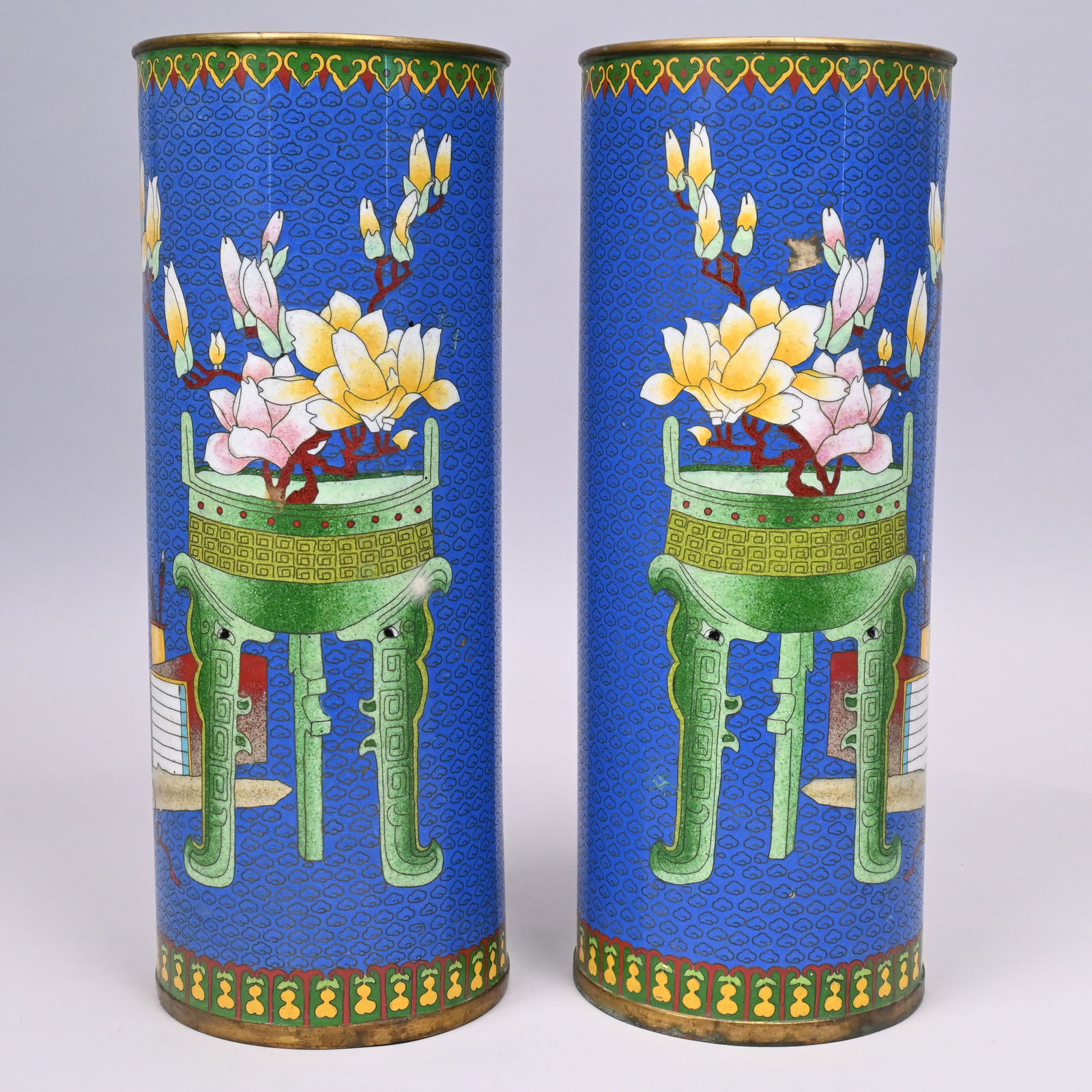 Pair of Chinese Cloisonne Enamel Cylinder Vases: Pair of Chinese Cloisonne Enamel Tall Cylinder Vases, Guangxu. Each enamelled in pink, yellow and green with magnolia branches issuing from a green jardiniere on stand, a group of scholar's objects
