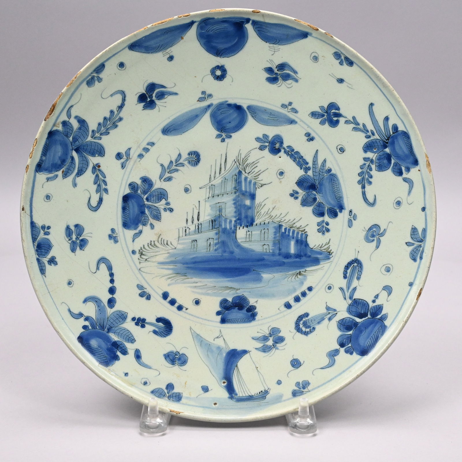 Dutch Delft Blue and White Tazza: Dutch Delft Blue and White Tazza, Late 17th-Early 18th Century. Painted in the center with a roundel edged with fruit and flowers and enclosing a large building, and on the wide rim with a sailing