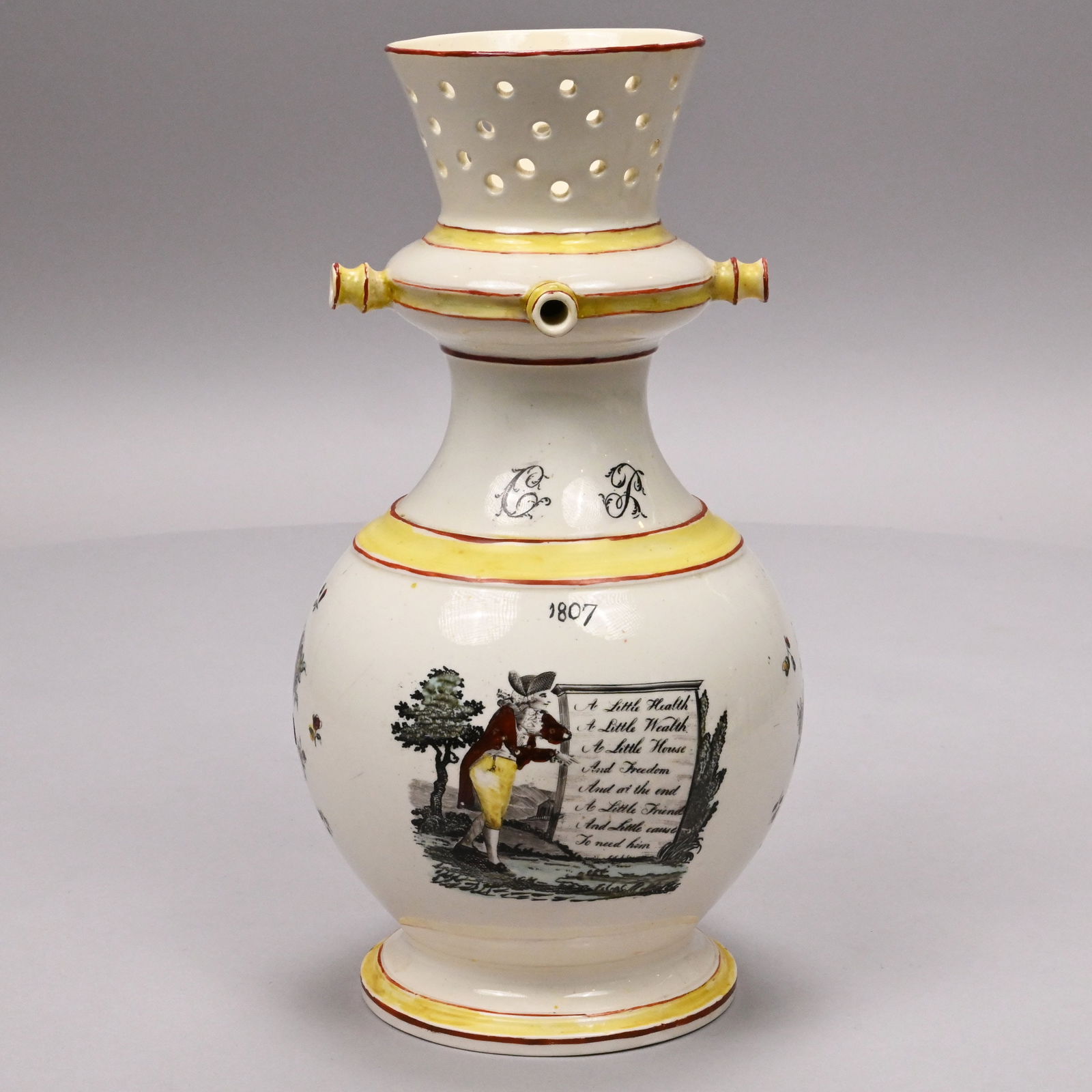 English Creamware Printed and Enamelled Puzzle Jug: English Creamware Transfer-Printed and Enamel-Decorated Puzzle Jug, Dated 1807. Of bulbous form with pierced flared rim above three nozzles, printed on the neck with the initials "CL" in black