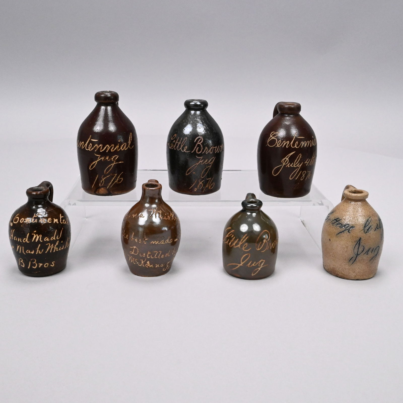 Seven Stoneware Souvenir and Advertising Jugs: Seven American Glazed Stoneware Miniature Advertising and Souvenir Jugs, Most Attributed to the Norton Family, Bennington, Vermont, Fourth Quarter 19th Century. Four covered in Albany slip, all